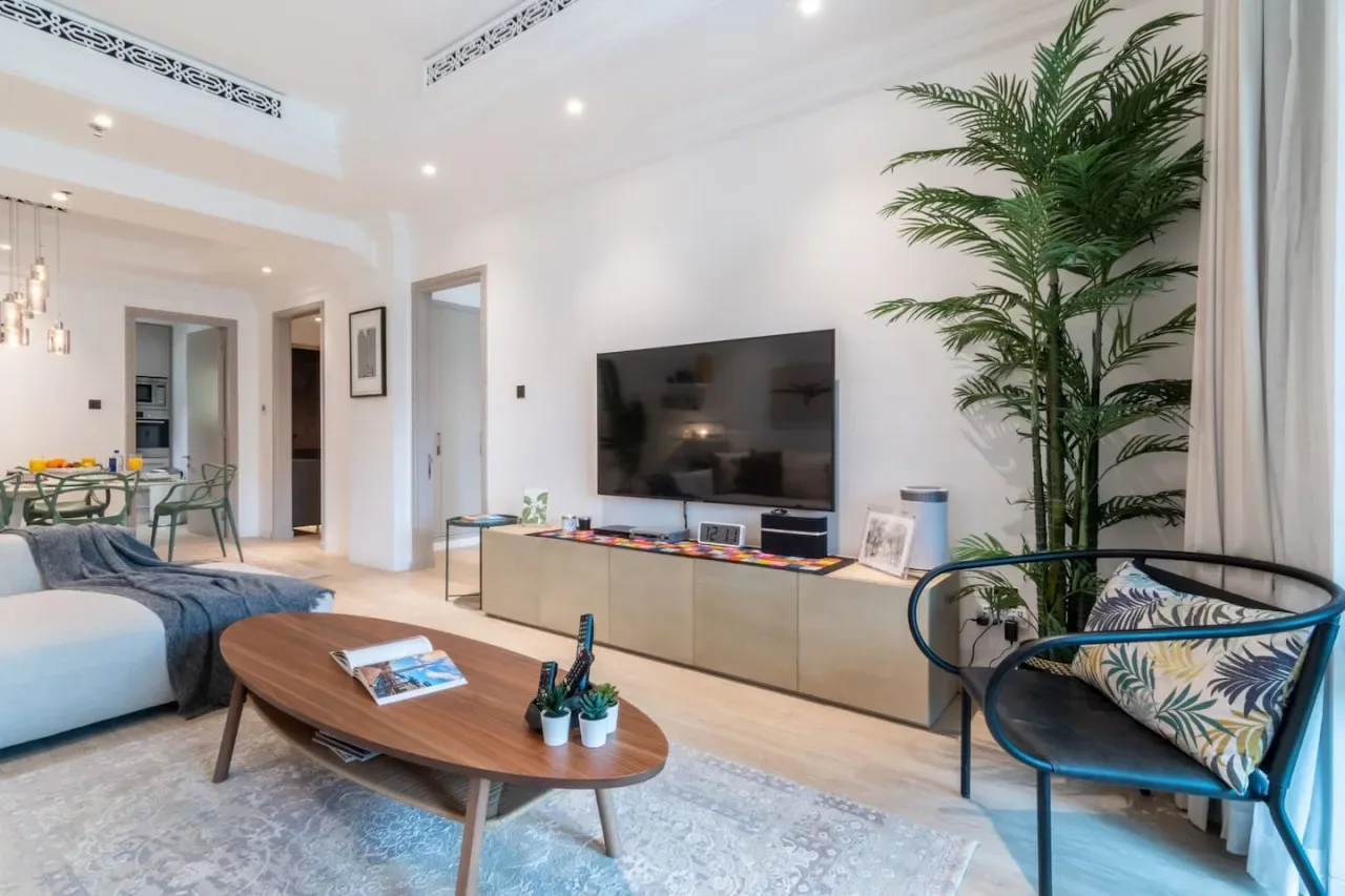 A bright living room with a television, seating, and a tall indoor plant.