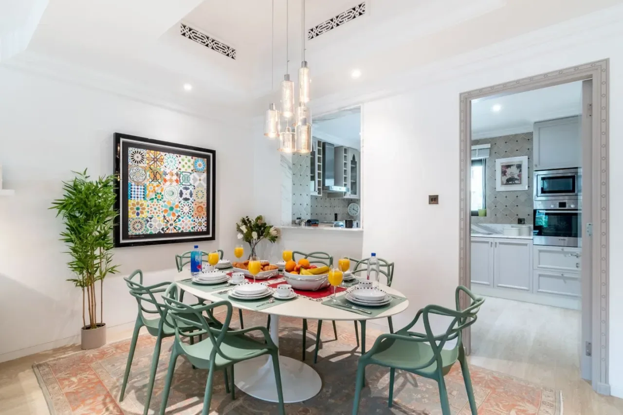 A bright dining area with a set table and colorful framed artwork.