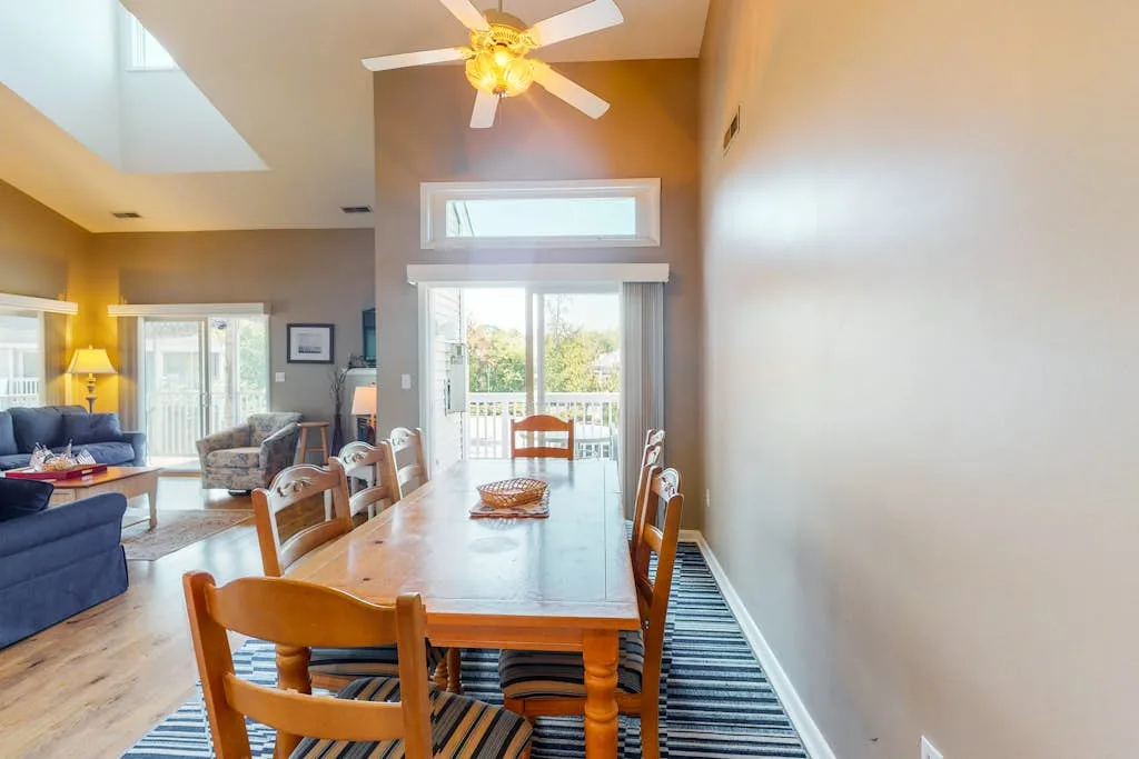 A dining area with a wooden table and chairs beside bright patio doors.