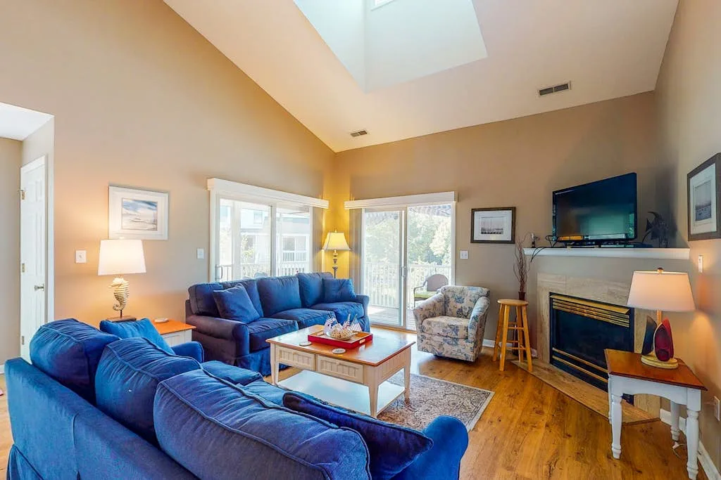 A bright living room with blue seating, a coffee table, and a fireplace.