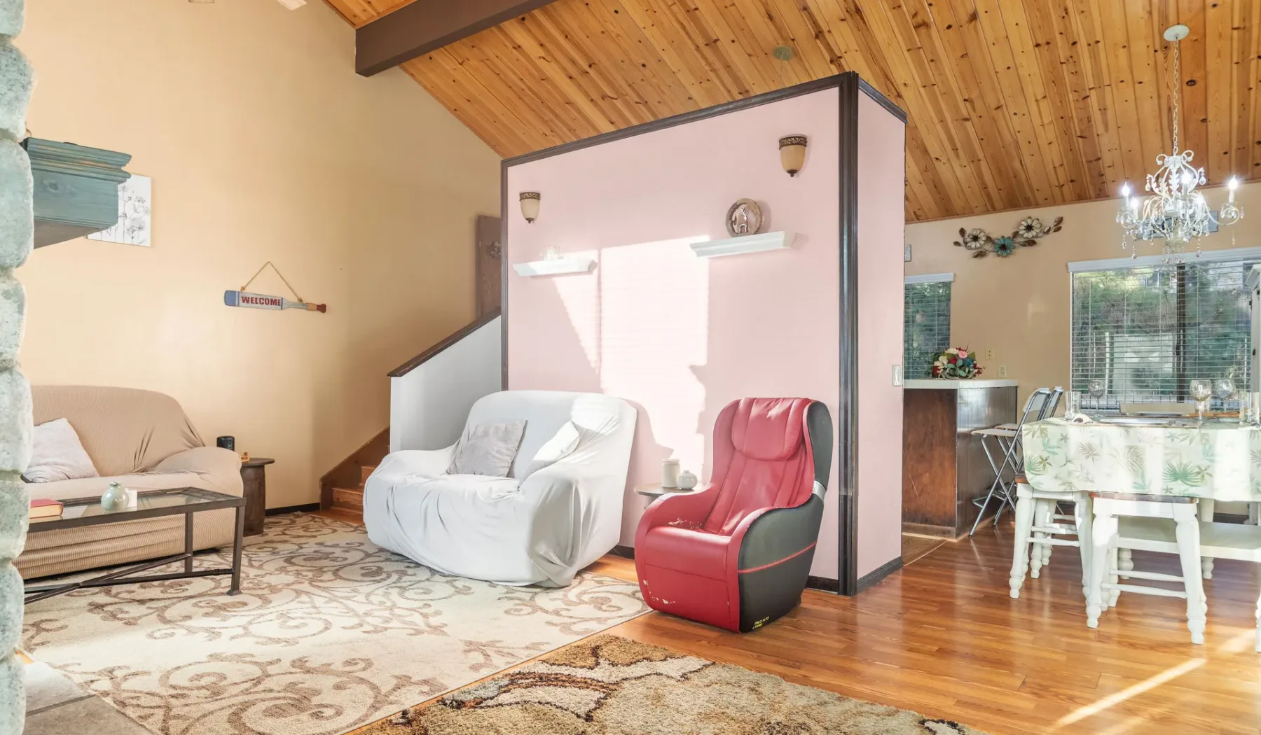 A bright living and dining area with seating beneath a sloped wood ceiling.