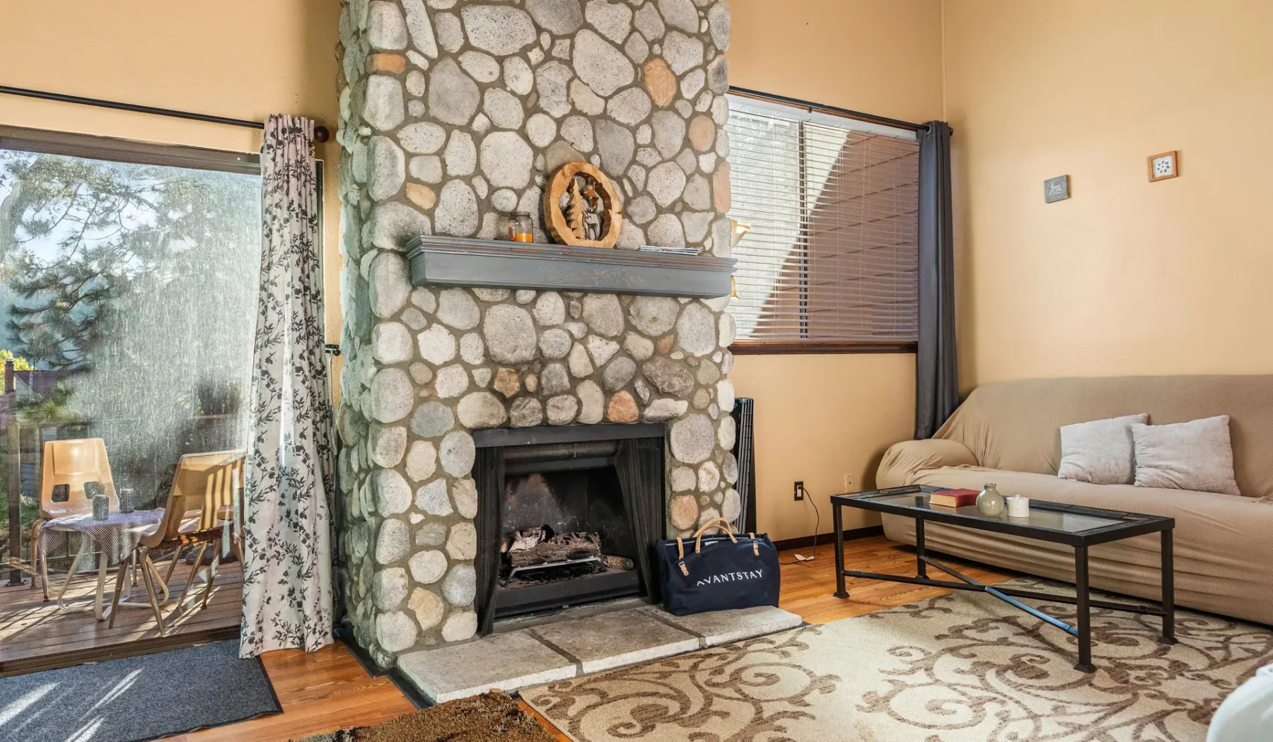 A living room with a stone fireplace and seating beside a glass door.