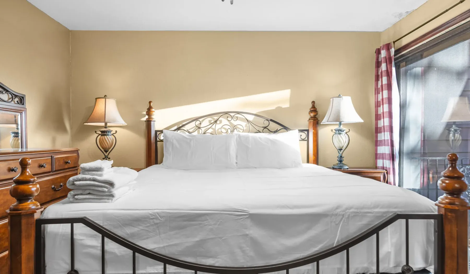 A bedroom with a large bed, bedside lamps, and a glass door.