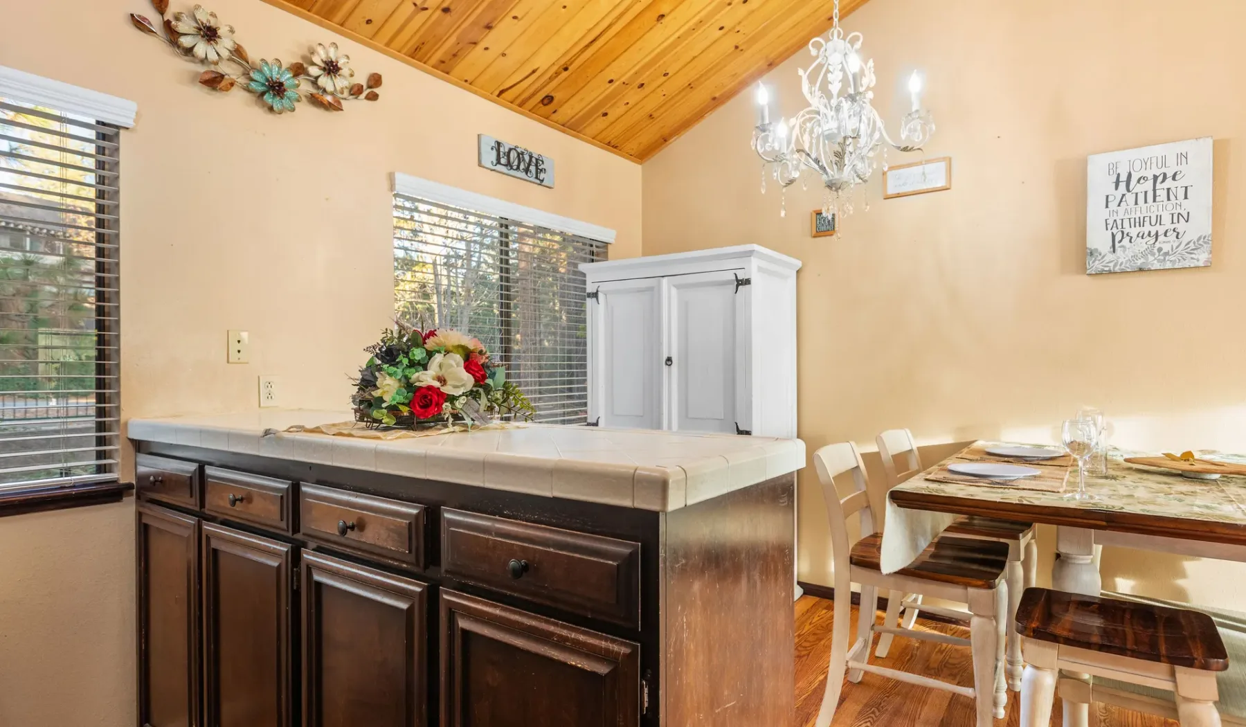 A dining area with a wooden table, chairs, and a dark kitchen island.