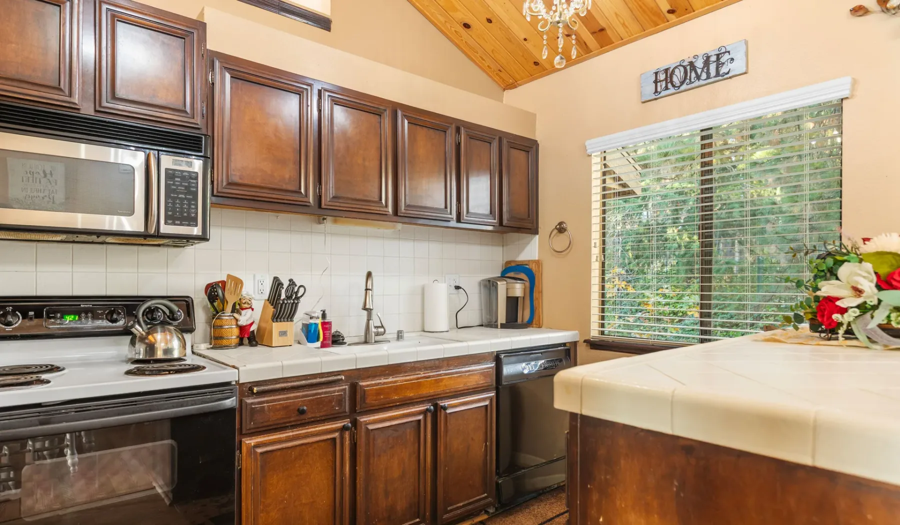 A kitchen with dark wood cabinets, stainless steel appliances, and a large window.