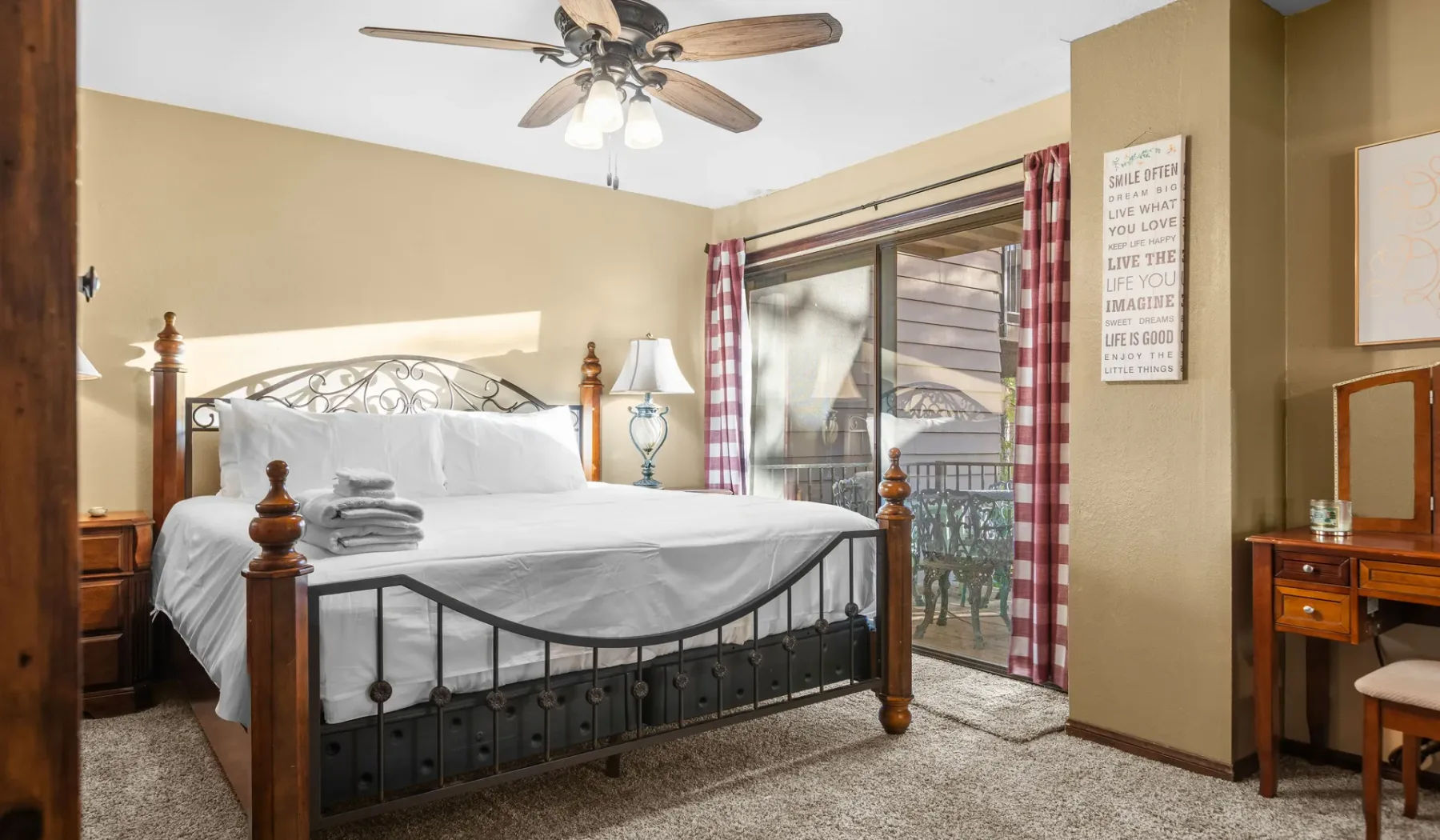 A bedroom with a bed, sliding glass doors, and red-and-white curtains.