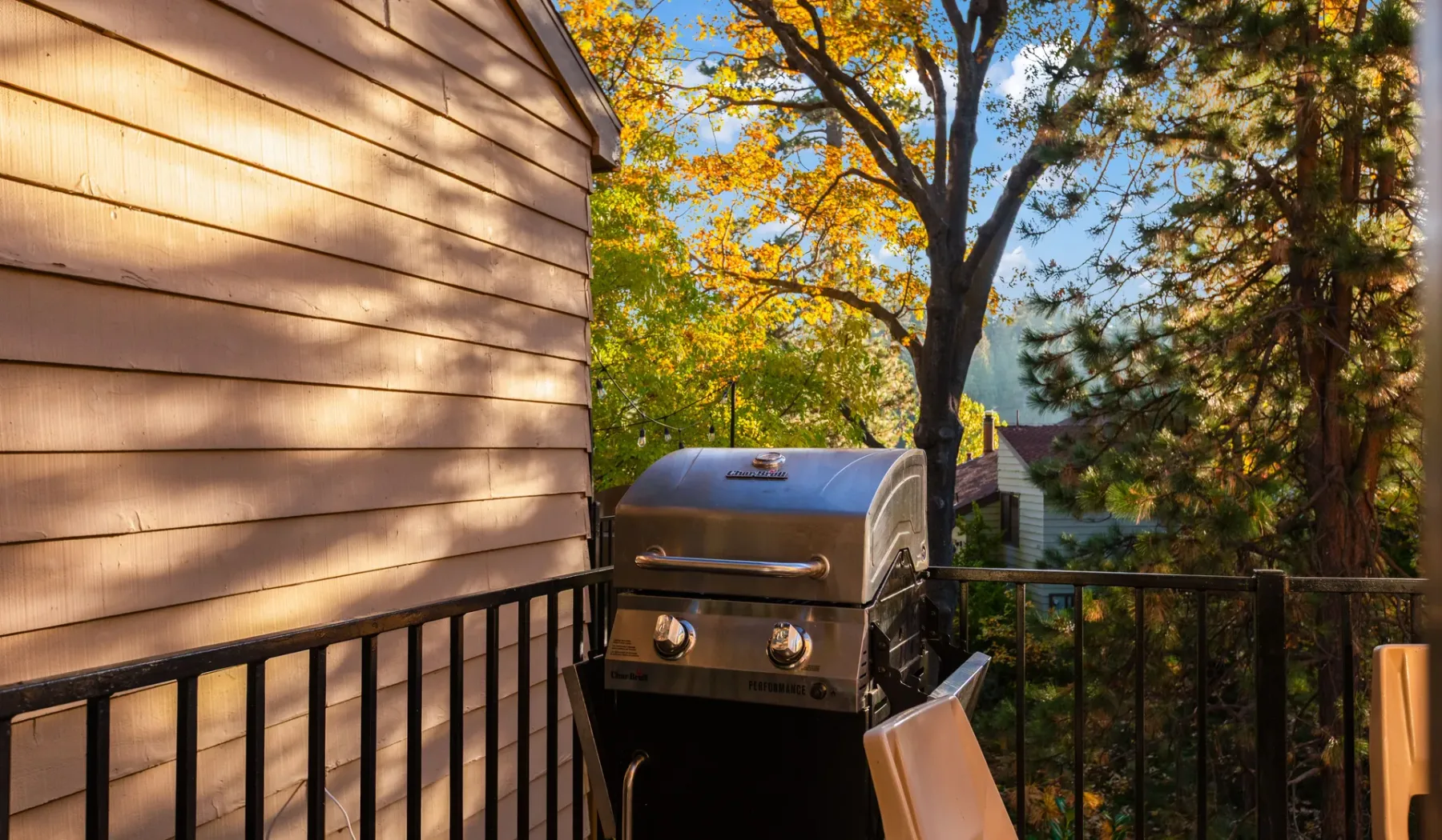 A deck with a barbecue grill overlooks leafy trees.
