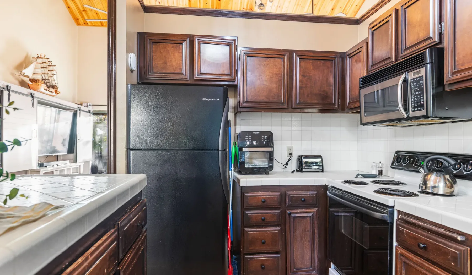 A compact kitchen with dark wood cabinets, a refrigerator, and a stove.