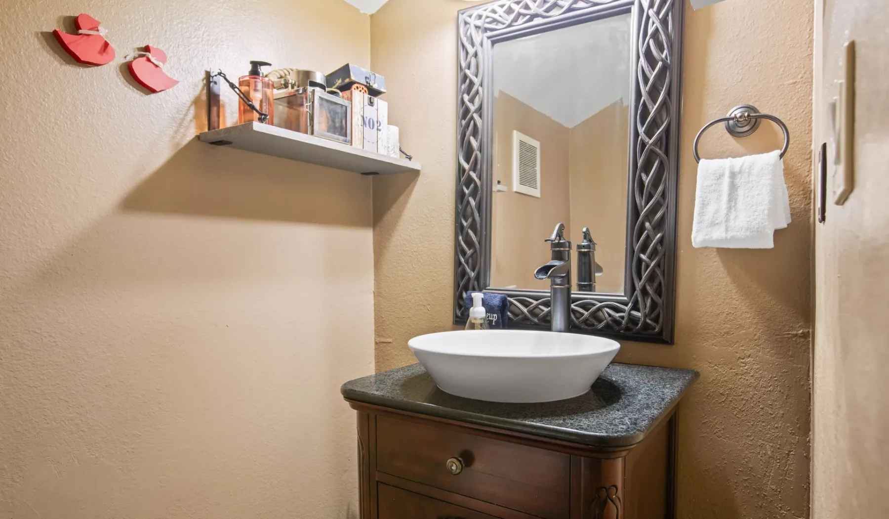 A bathroom vanity with a vessel sink, mirror, and towel ring.