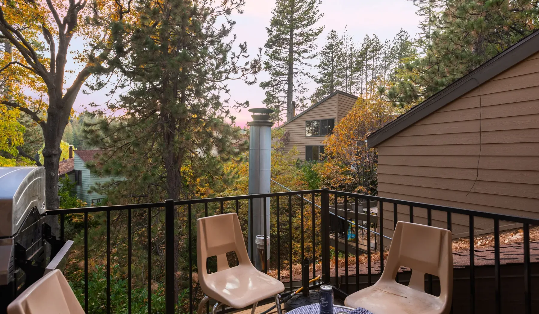 A balcony with seating overlooks trees and neighboring buildings.