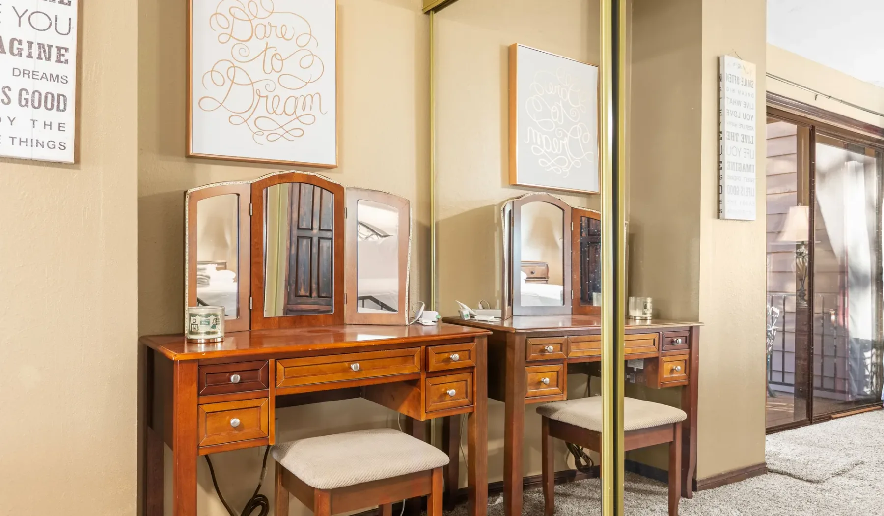 A bedroom dressing area with wooden vanities, mirrors, and upholstered seating.