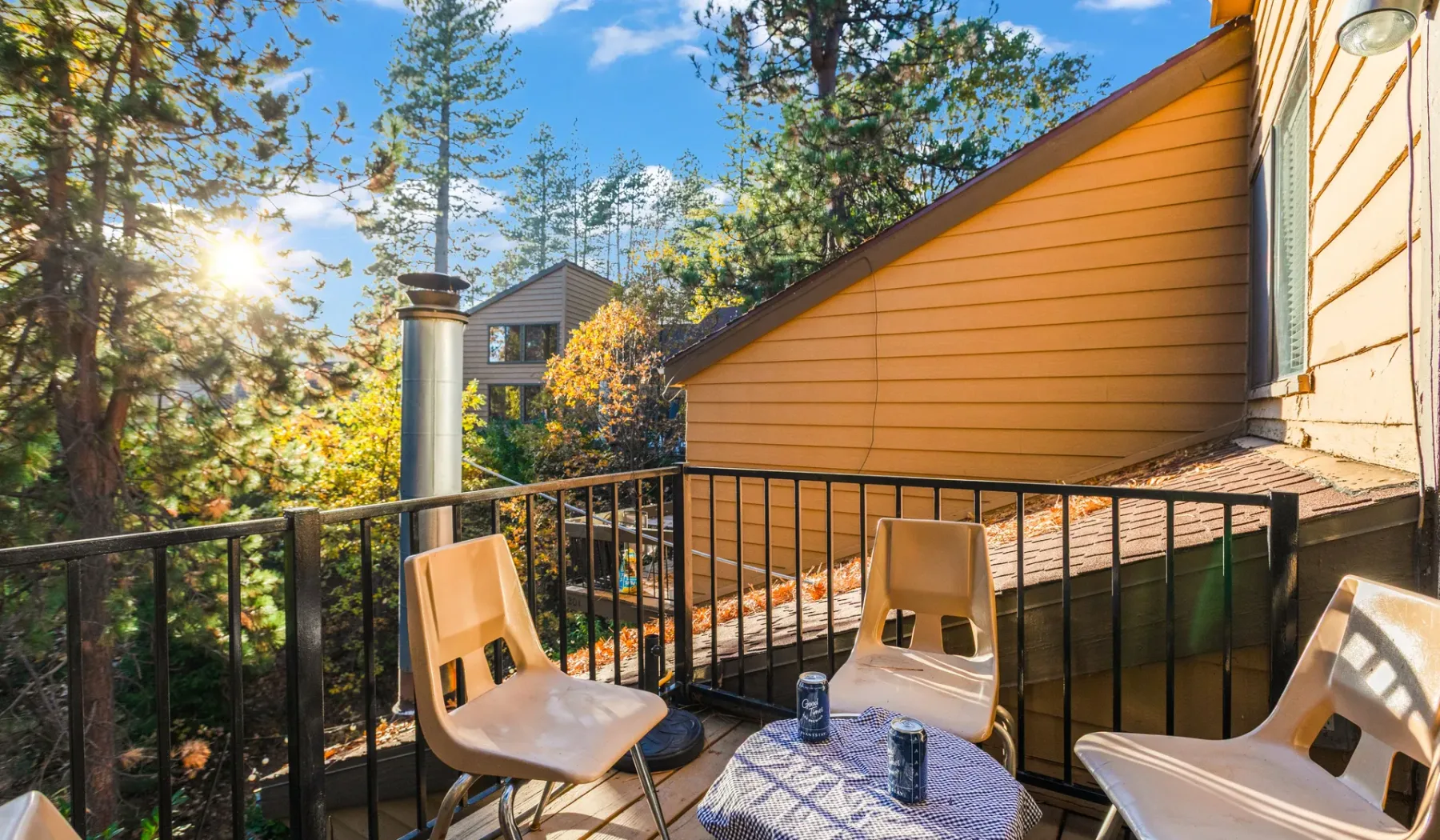 A balcony seating area overlooks leafy trees beside an orange-sided building.