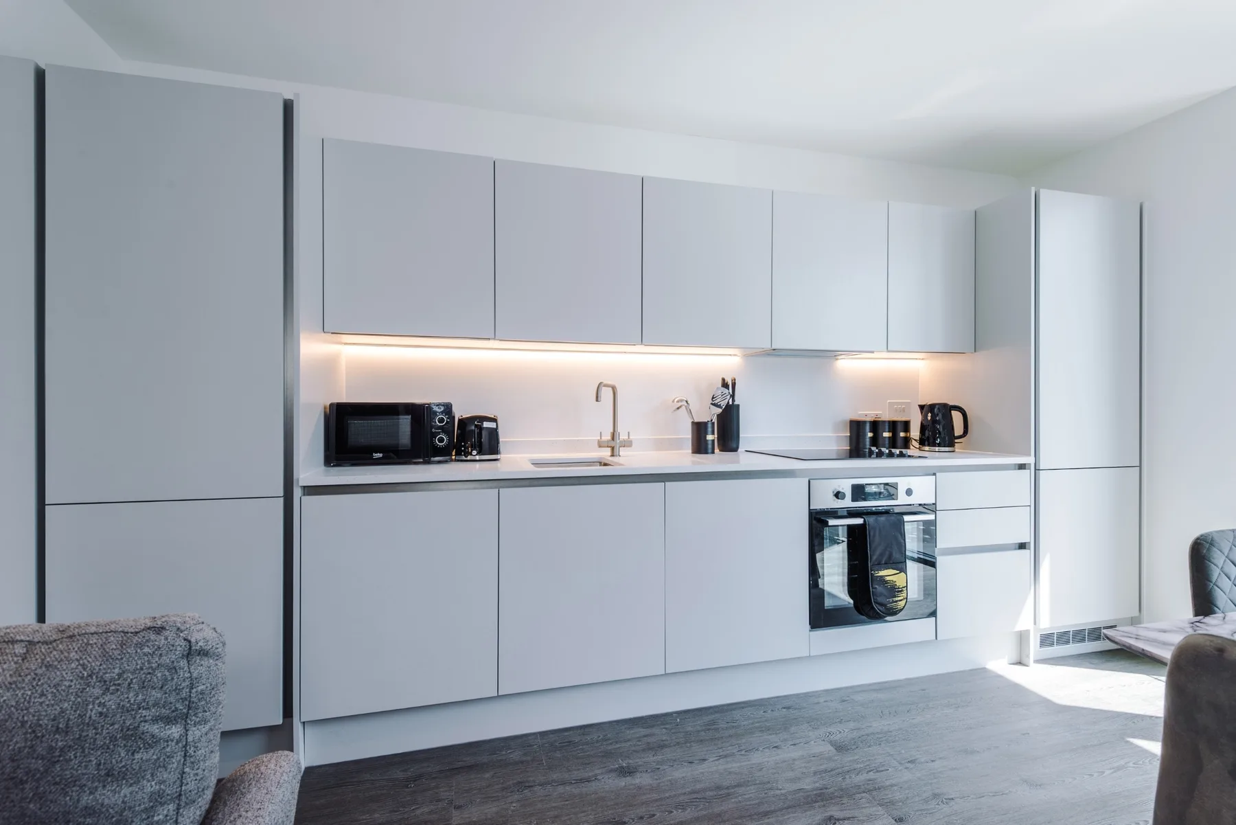 Una cocina moderna con gabinetes claros, encimera y electrodomésticos integrados.