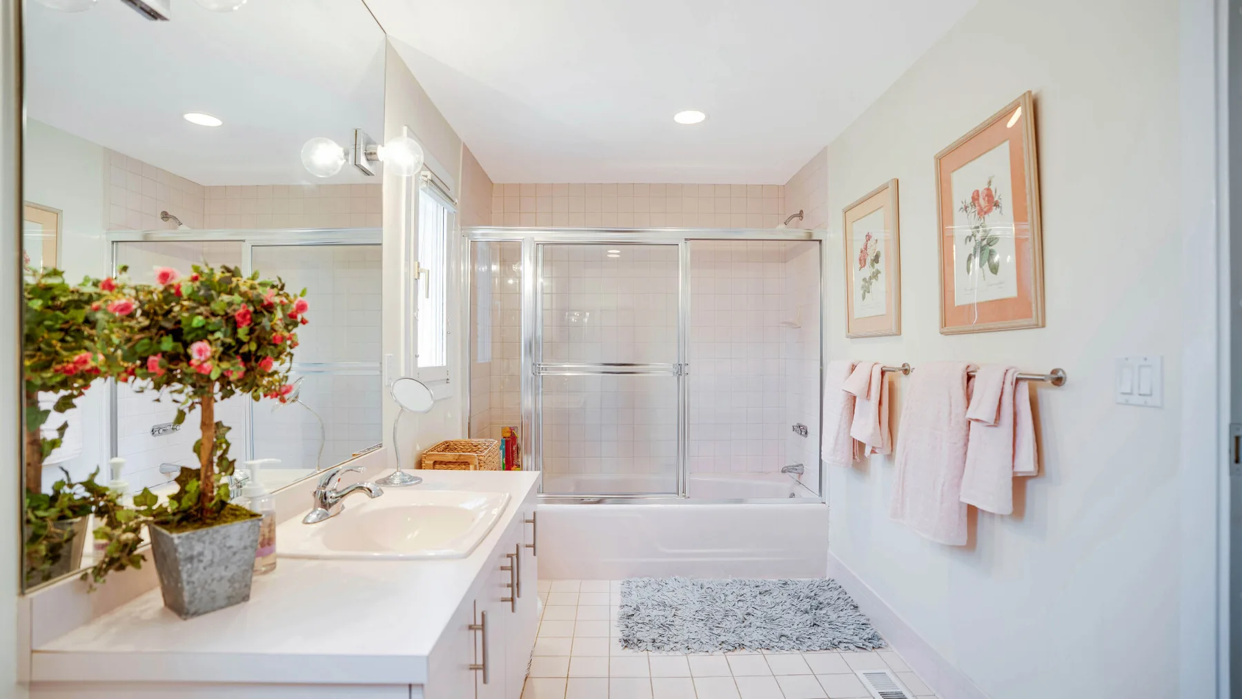 Un baño luminoso con bañera, paneles de ducha de vidrio y lavabo.