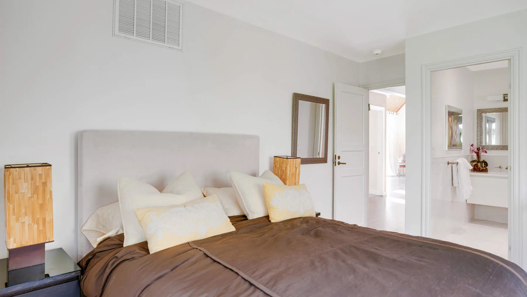Un dormitorio con una cama vestida con ropa de cama marrón y una puerta abierta.