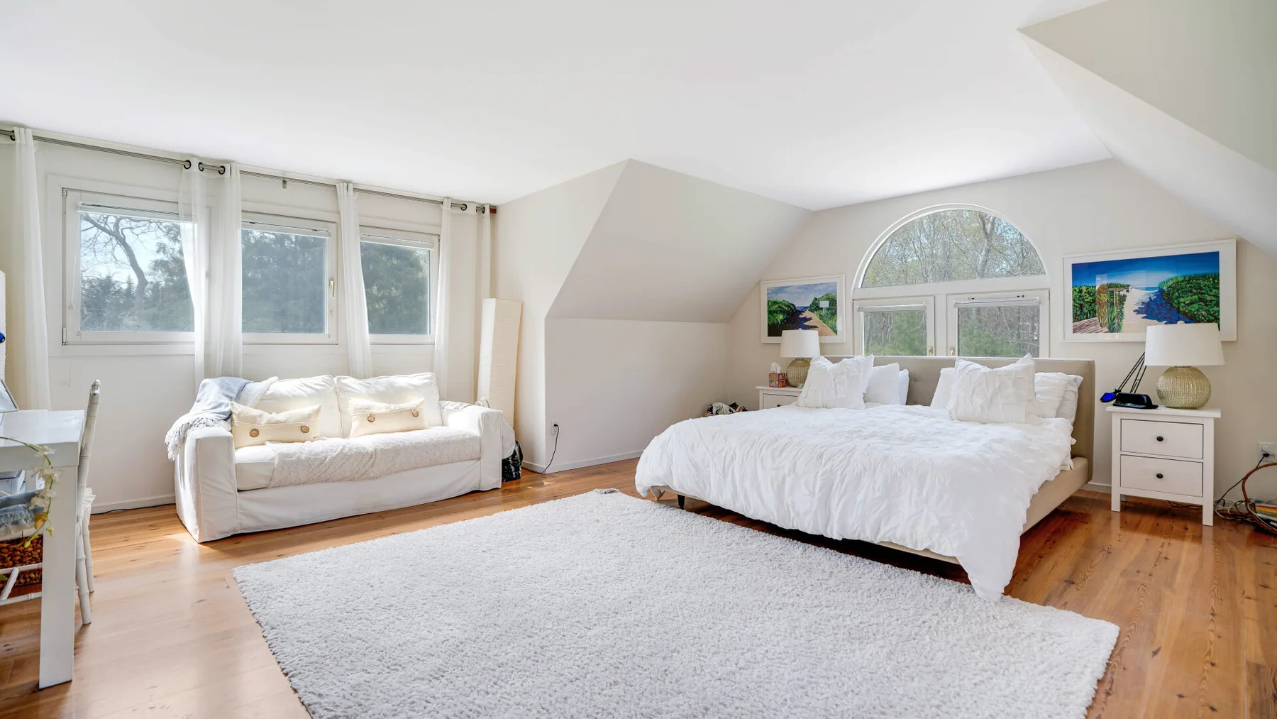 Dormitorio luminoso con una cama grande, un sofá y una alfombra.