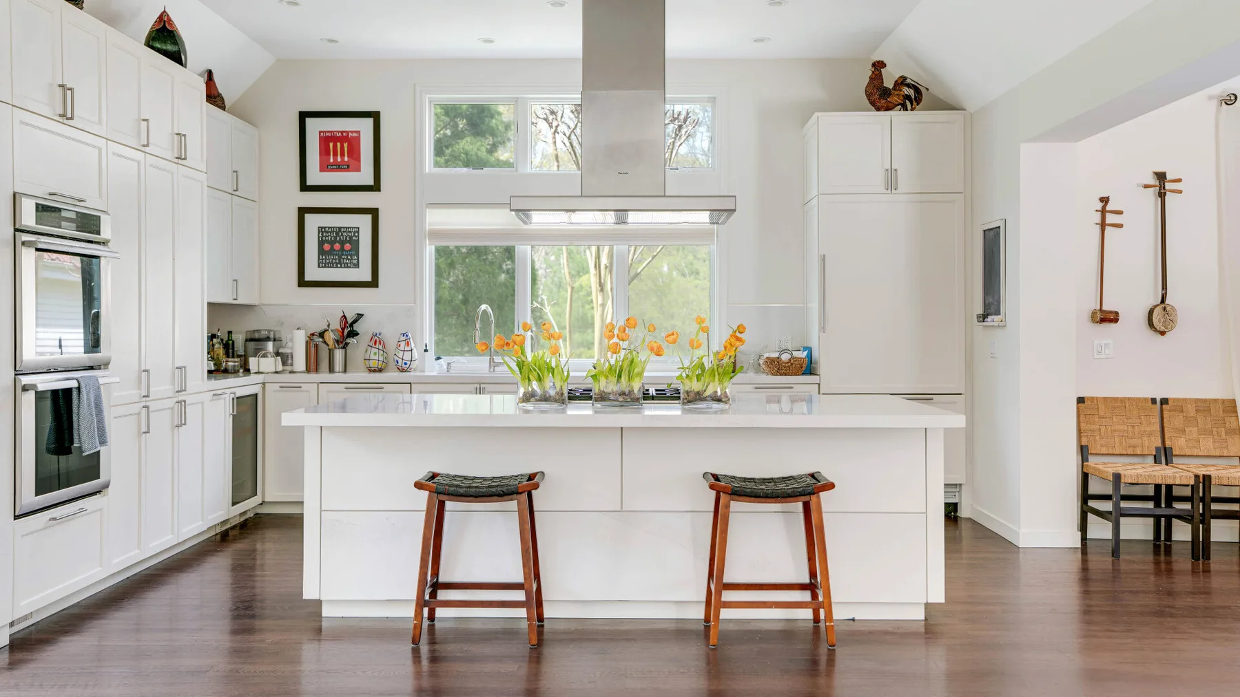 Una cocina luminosa con una isla central, taburetes y ventanas sobre la encimera.