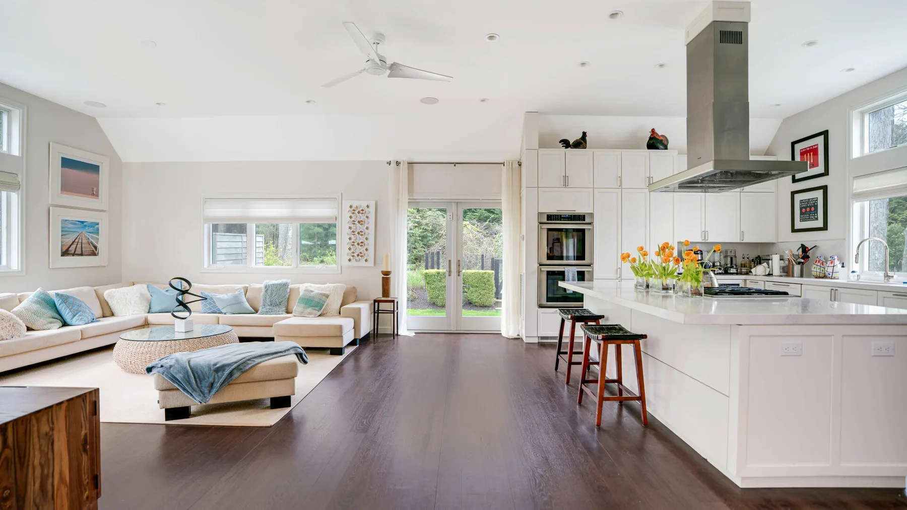 Sala de estar y cocina de concepto abierto con una isla blanca y asientos.