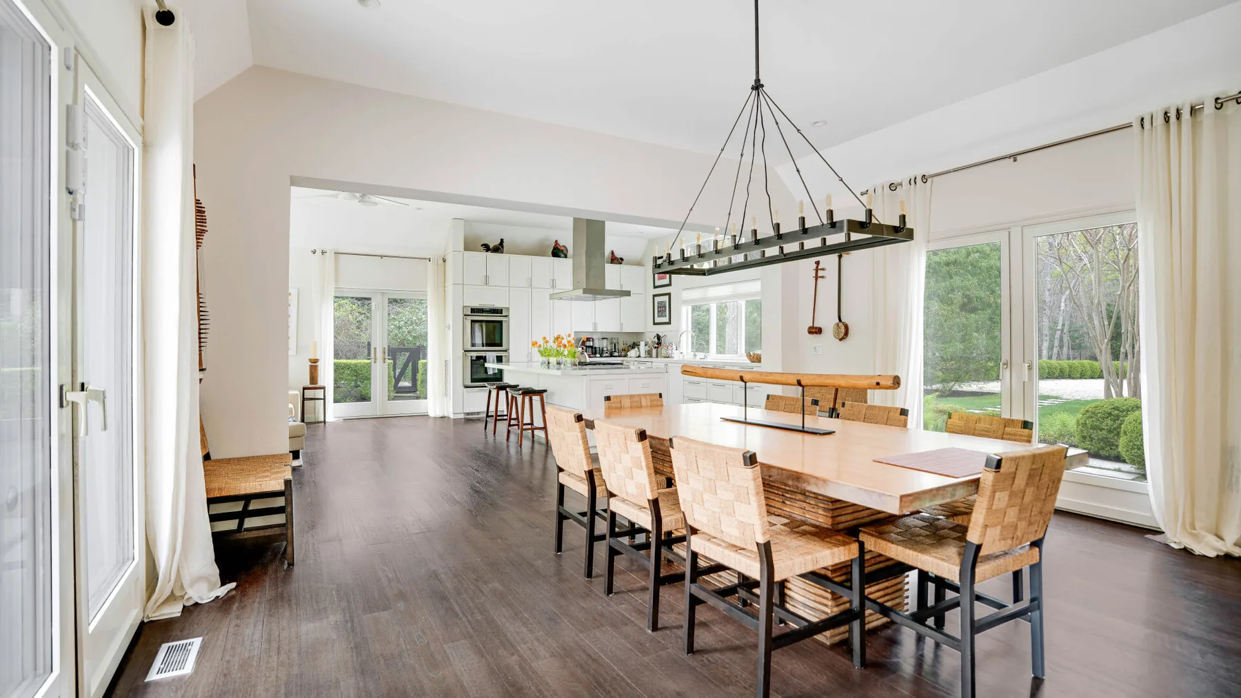 Un comedor luminoso con una mesa larga de madera y grandes ventanas.