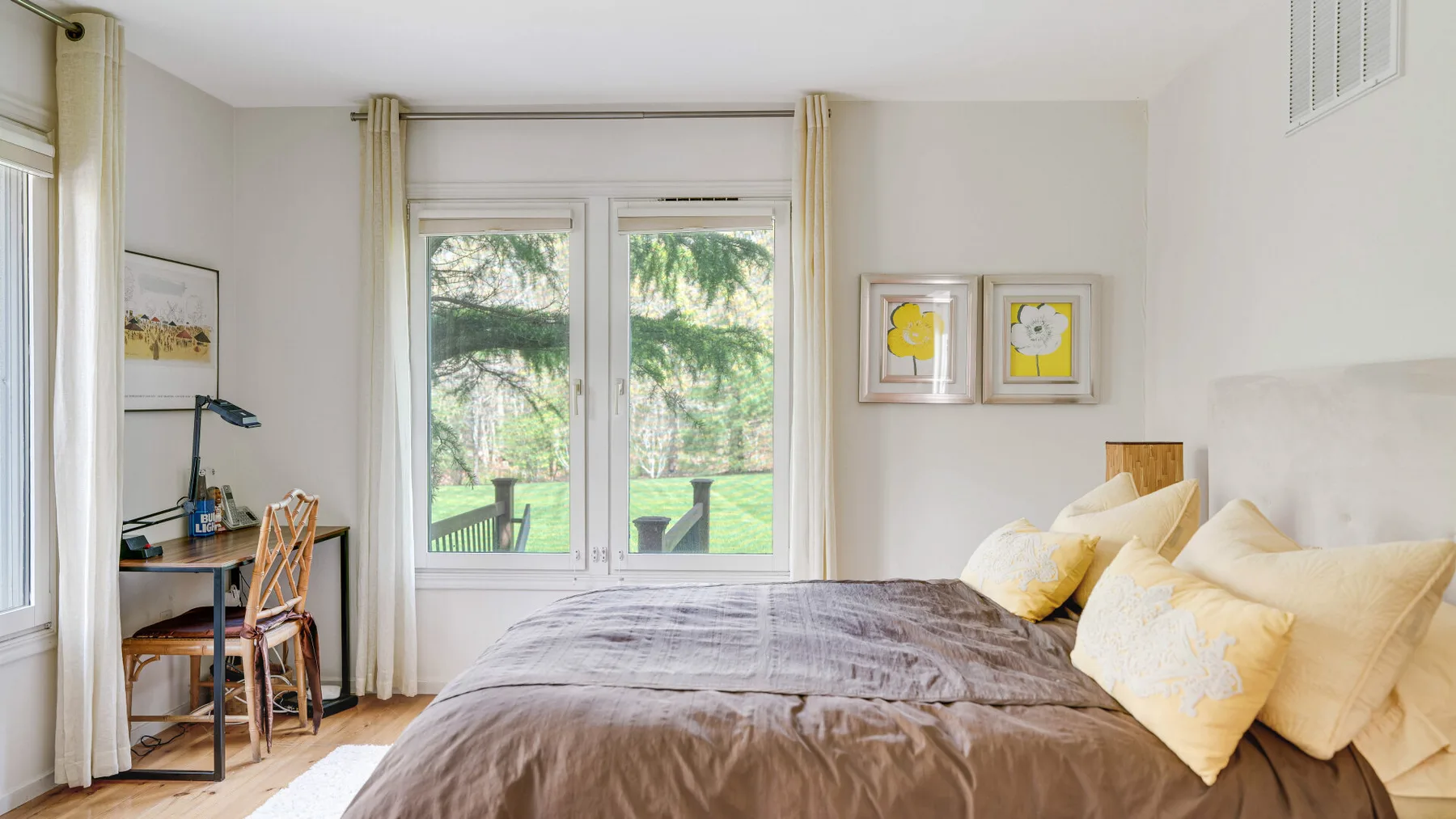Un dormitorio luminoso con una cama grande y ventanas con vistas a zonas verdes.