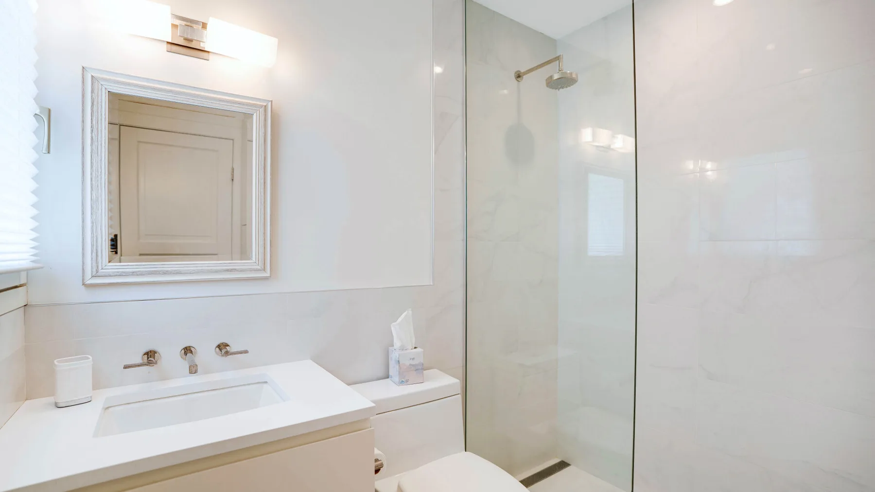 Un baño luminoso con lavabo y ducha de cristal.