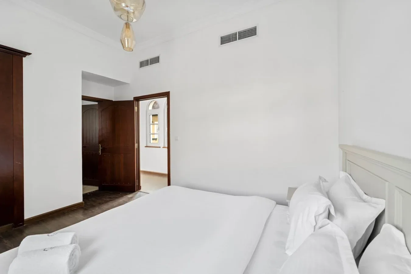 Un dormitorio con una cama bien tendida y una puerta abierta.