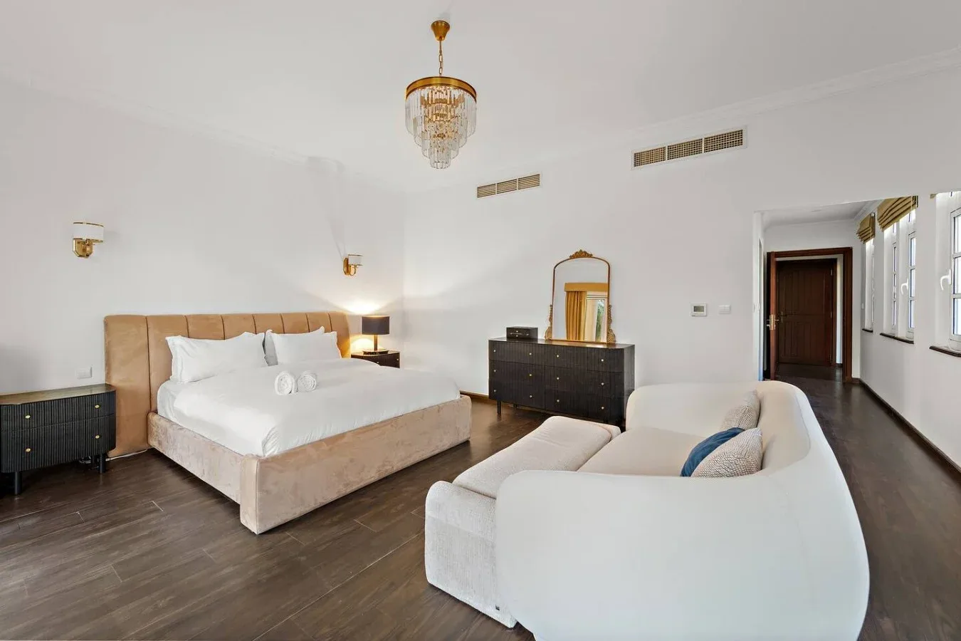 Un dormitorio luminoso con una cama grande y una zona de estar blanca.