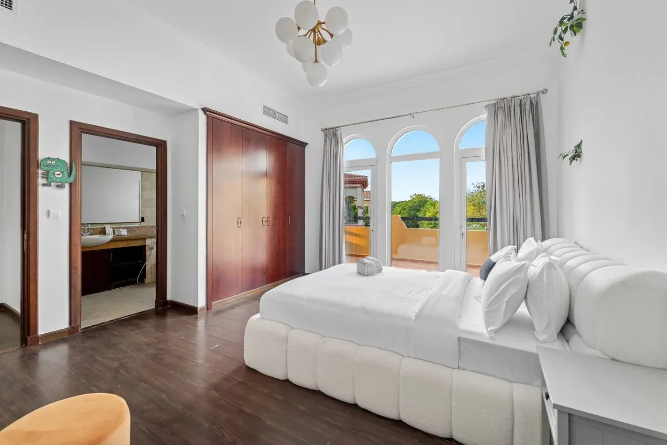 Un dormitorio luminoso con una cama grande junto a ventanas arqueadas.