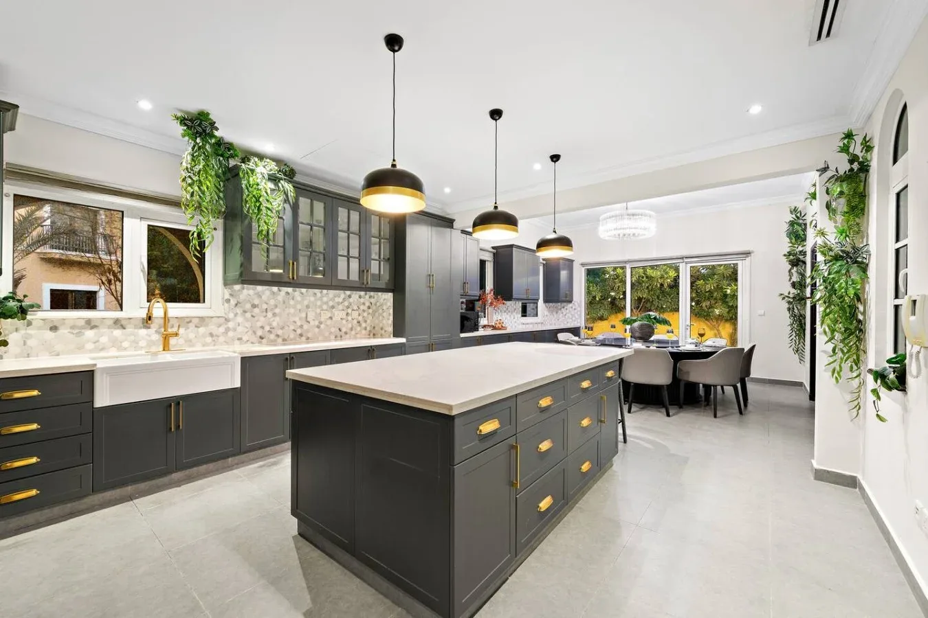Una cocina luminosa con gabinetes oscuros, una isla grande y lámparas colgantes.