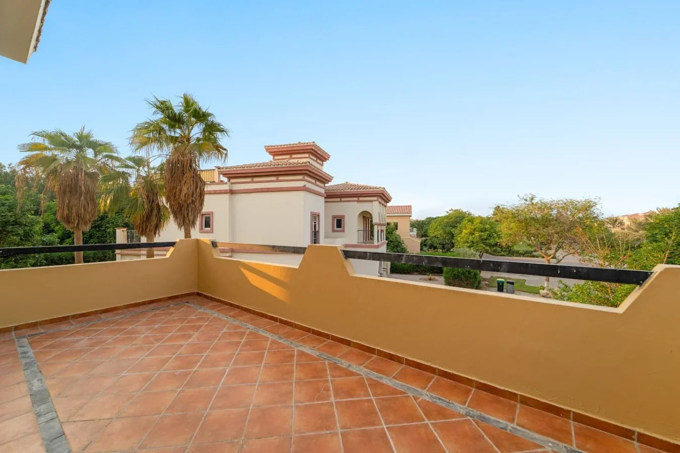 Una terraza embaldosada da a palmeras y edificios cercanos.