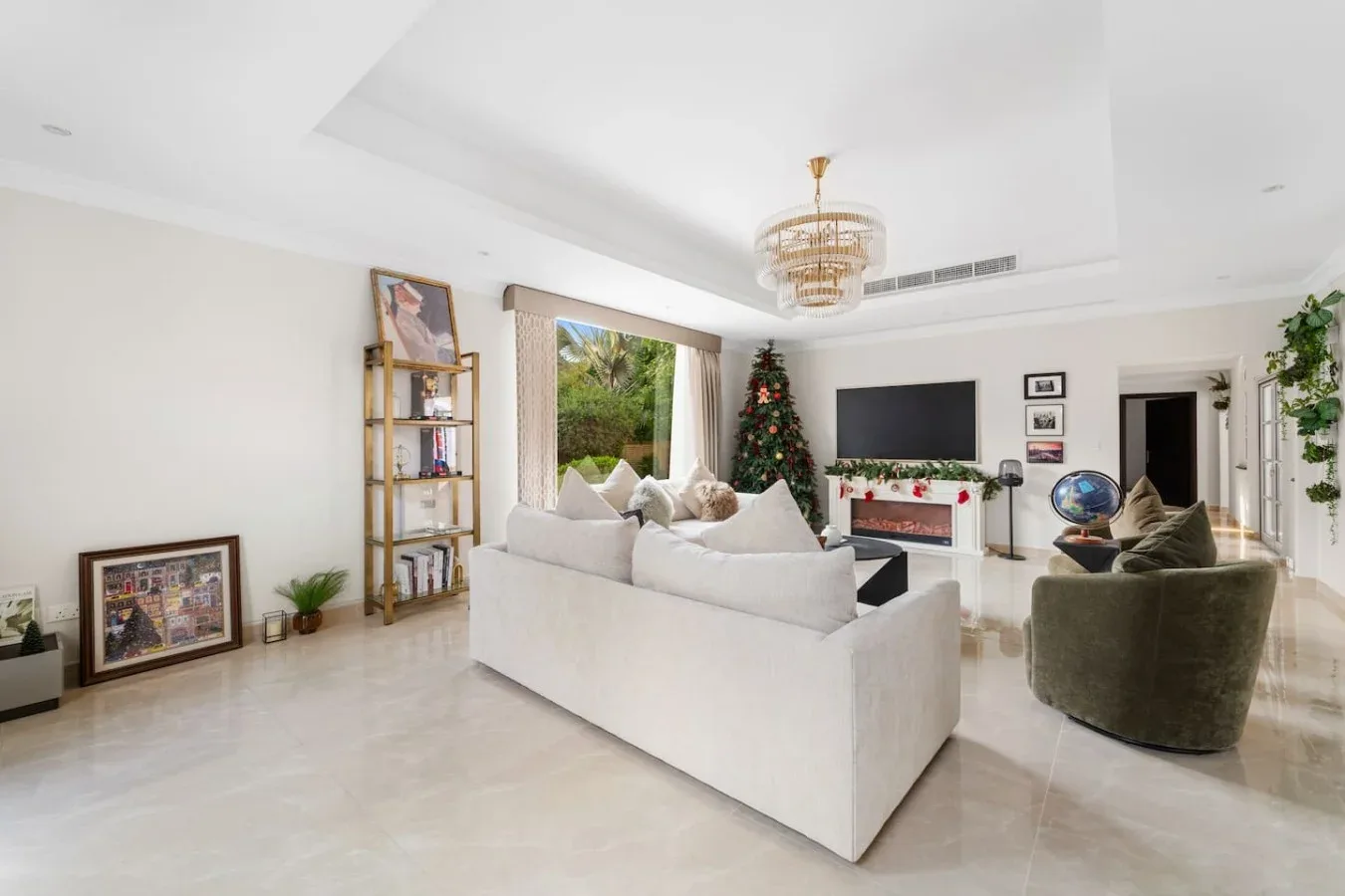 Una sala luminosa con asientos frente a un televisor y un árbol de Navidad decorado.