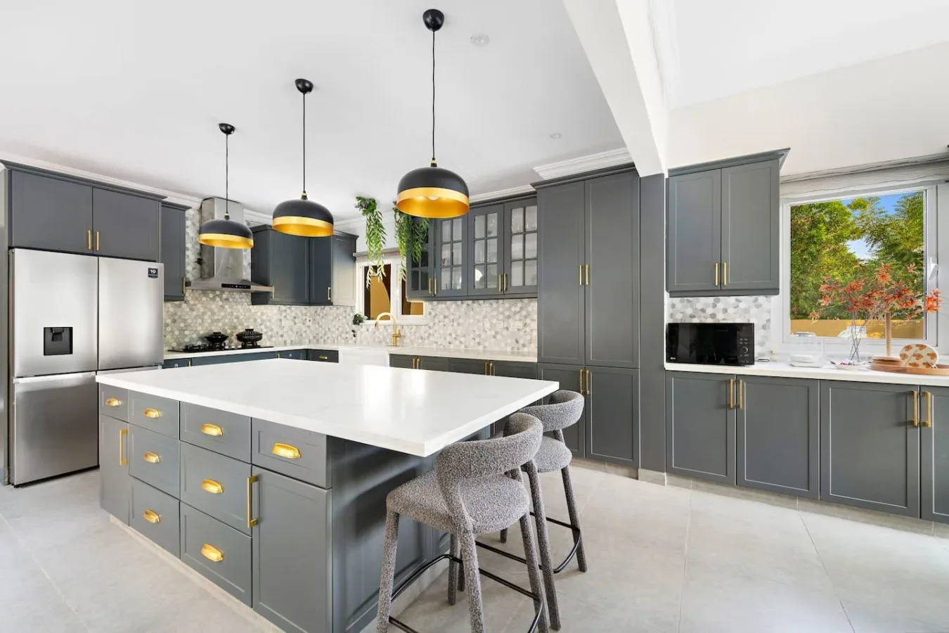 Una cocina moderna con gabinetes grises, una isla grande y luces colgantes.
