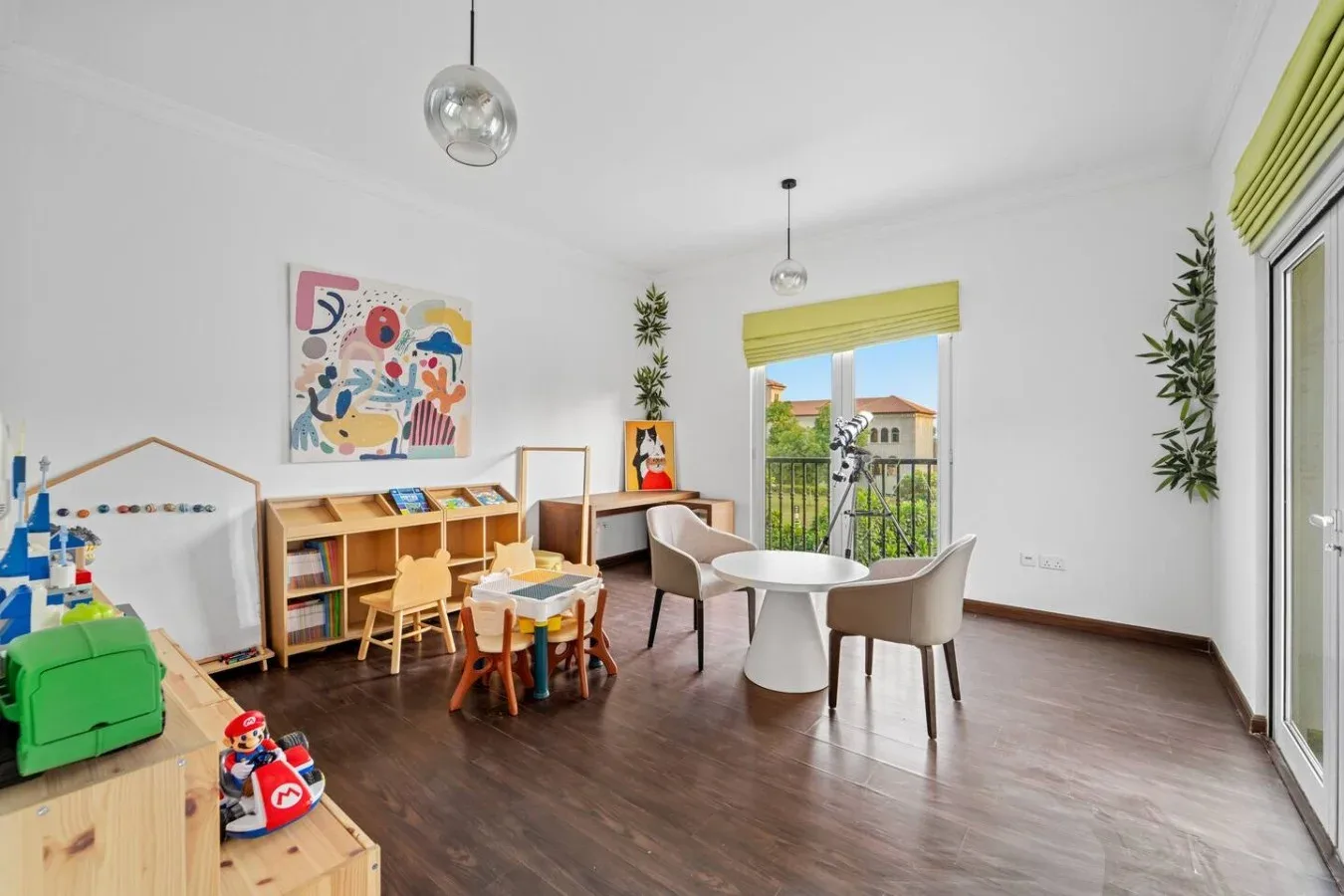 Una luminosa sala de juegos con una zona infantil y una mesa pequeña junto a las ventanas.