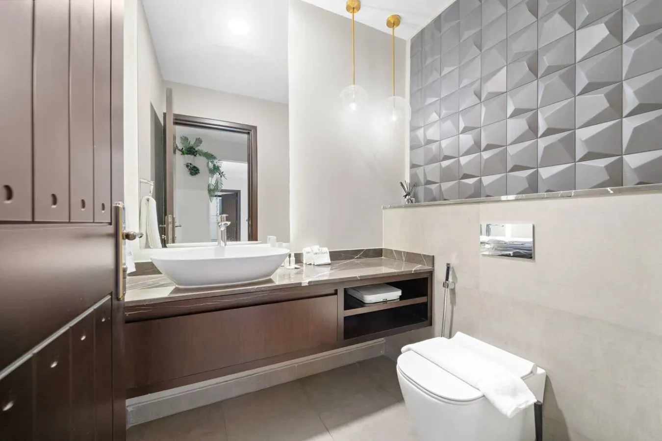Un baño moderno con un lavabo amplio, un lavabo sobre encimera y azulejos geométricos.