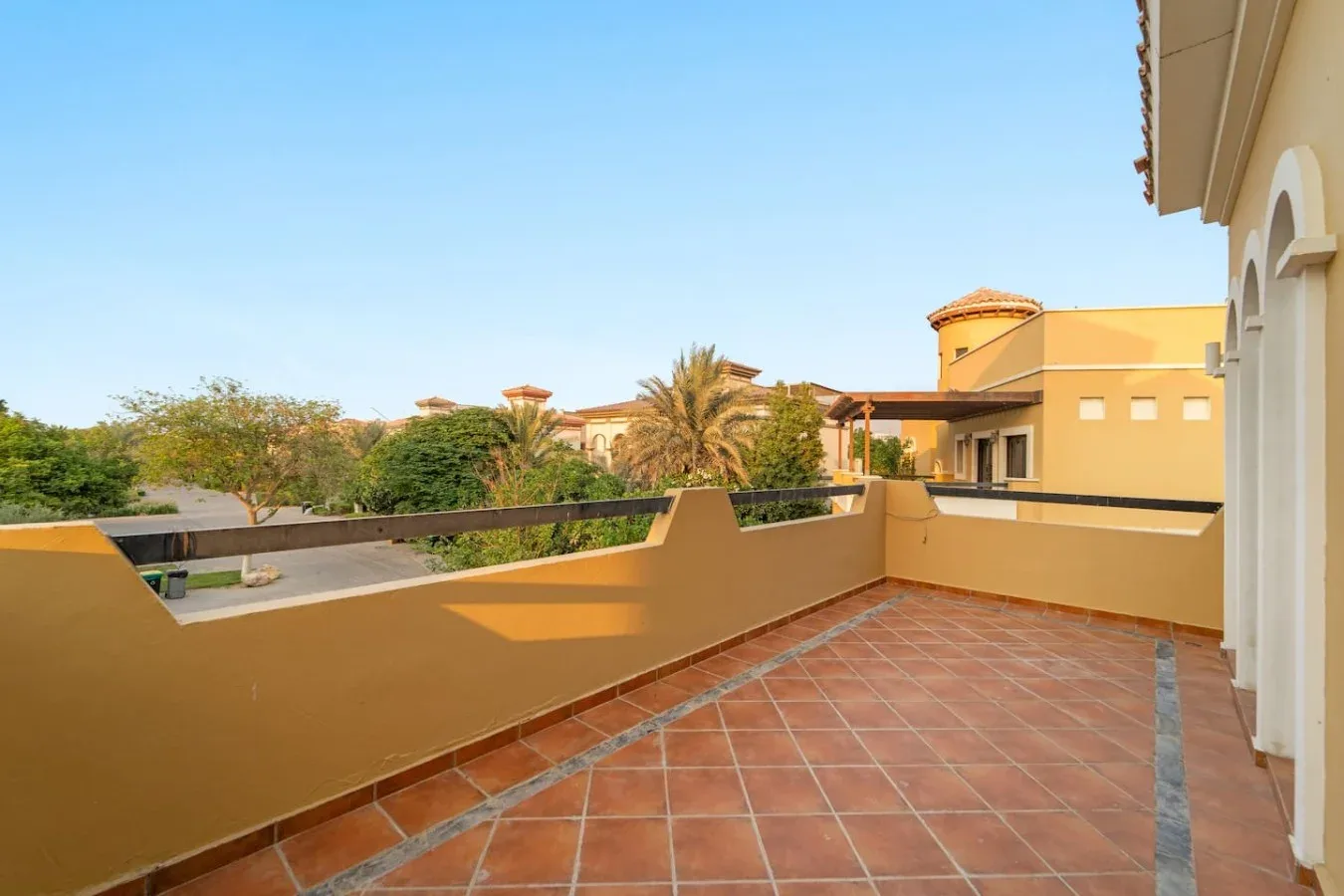 Una terraza embaldosada da a palmeras y edificios cercanos.