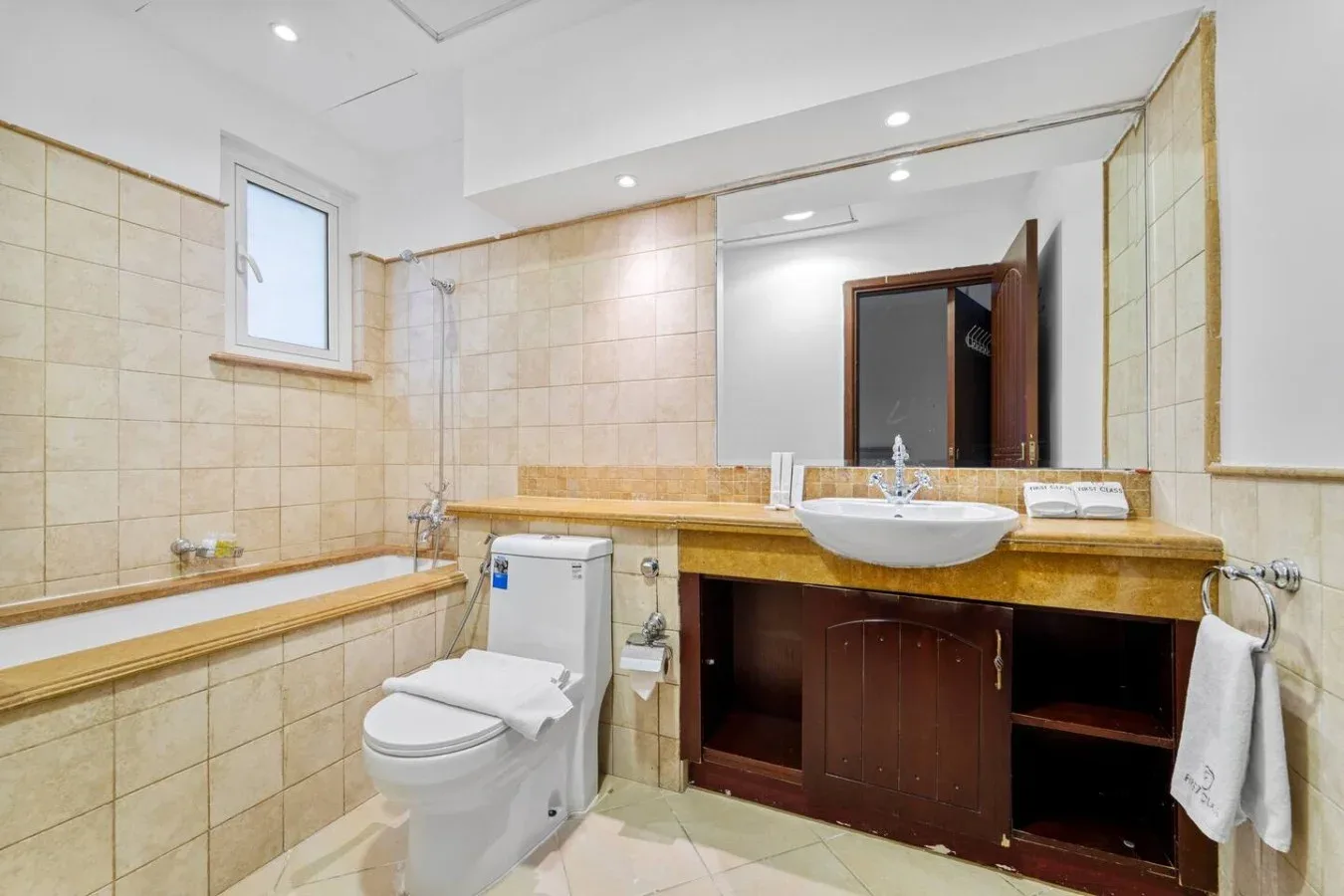 Un baño con azulejos, lavabo, inodoro y una encimera larga.