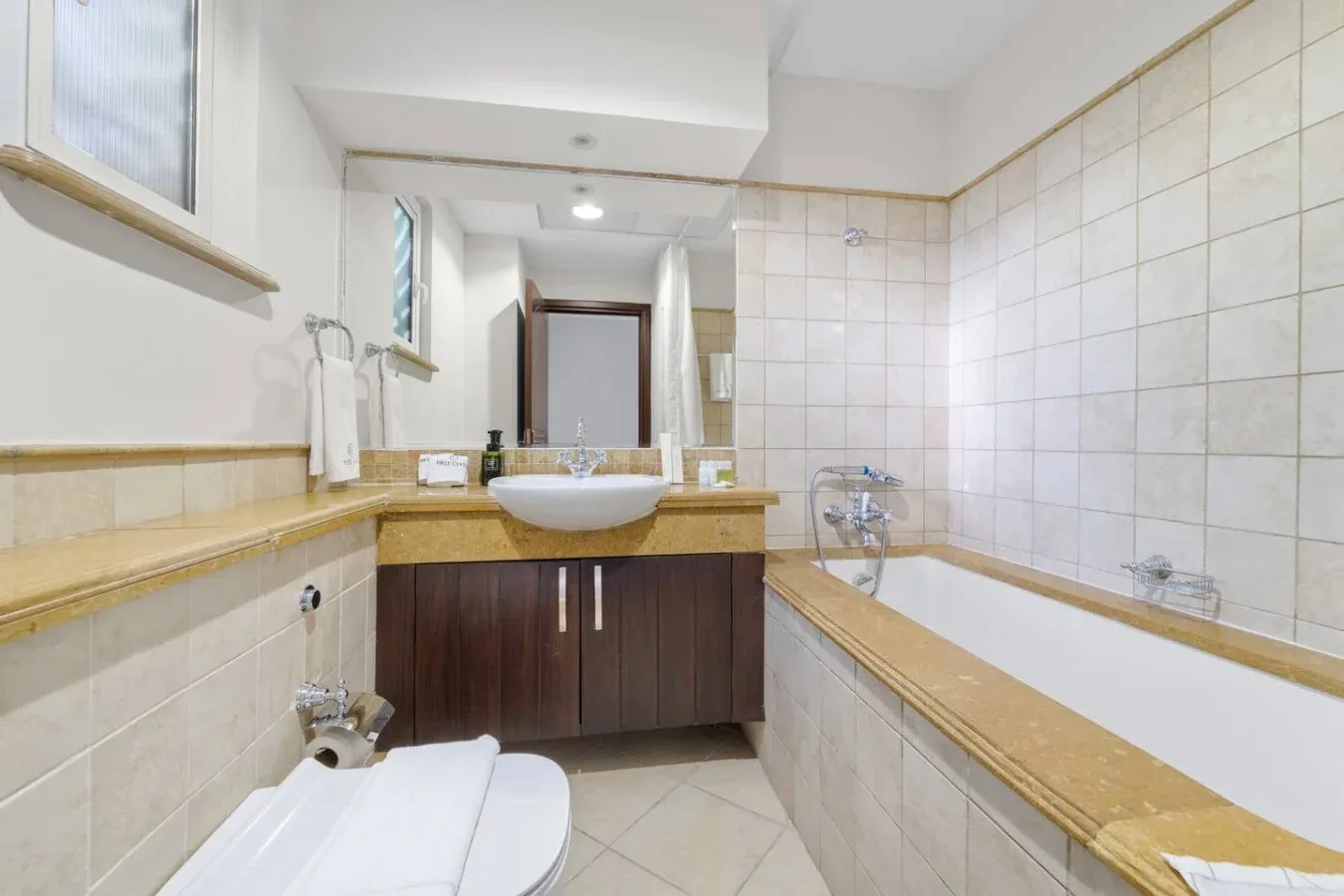 Un baño con azulejos, bañera, lavabo y sanitario.