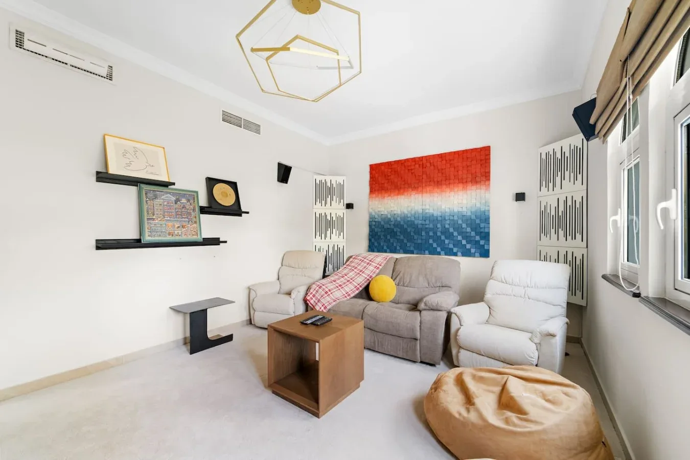 Sala de estar con asientos, una mesa de centro y arte colorido en la pared.