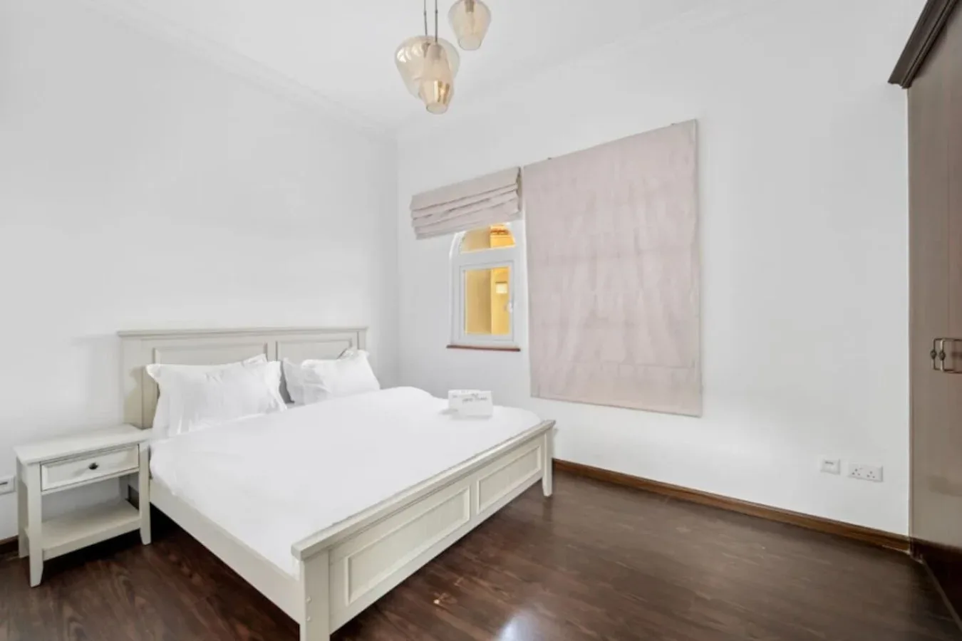 Un dormitorio luminoso con una cama bien hecha y una ventana pequeña.