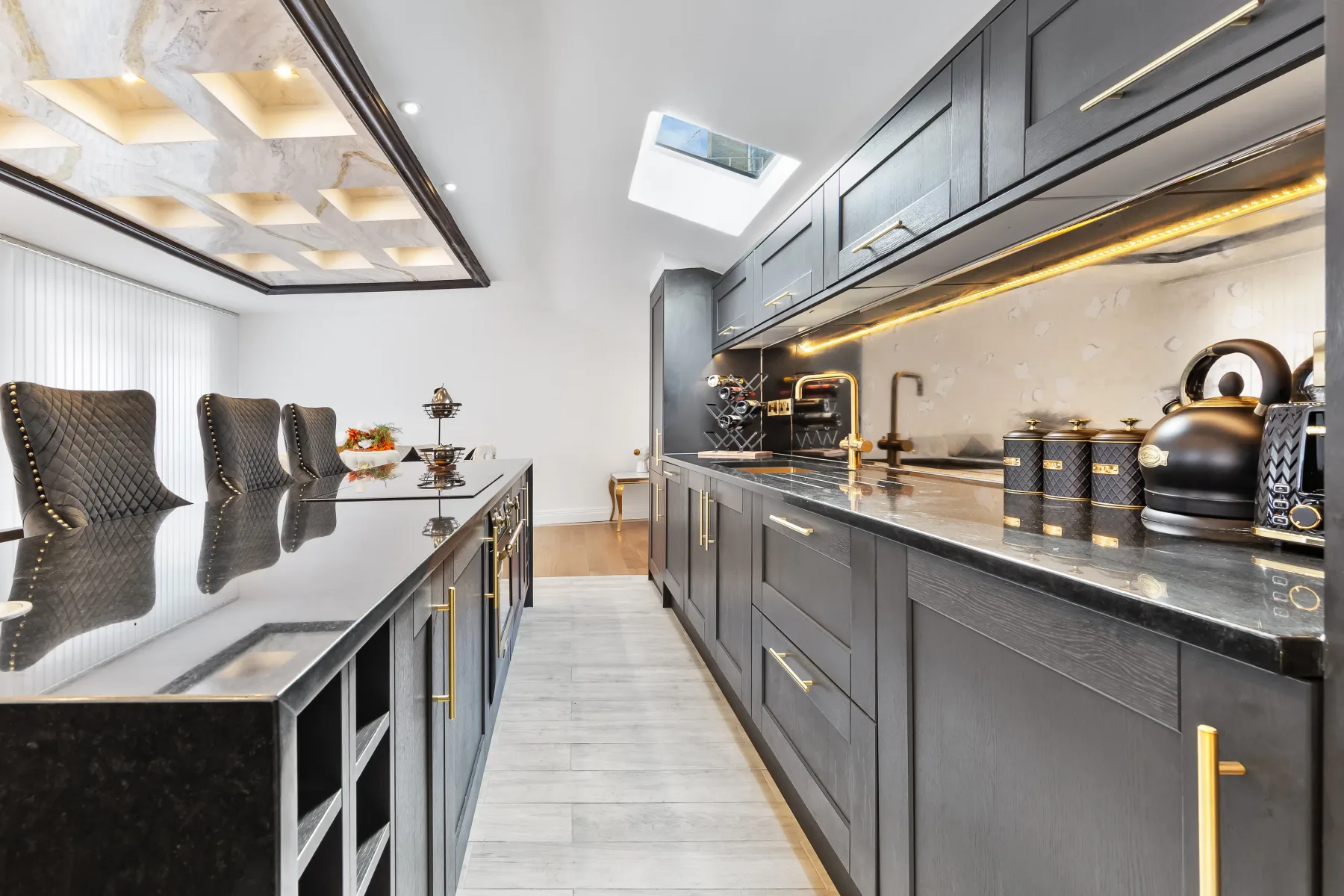 Una cocina moderna con gabinetes oscuros, una encimera larga y una isla central.