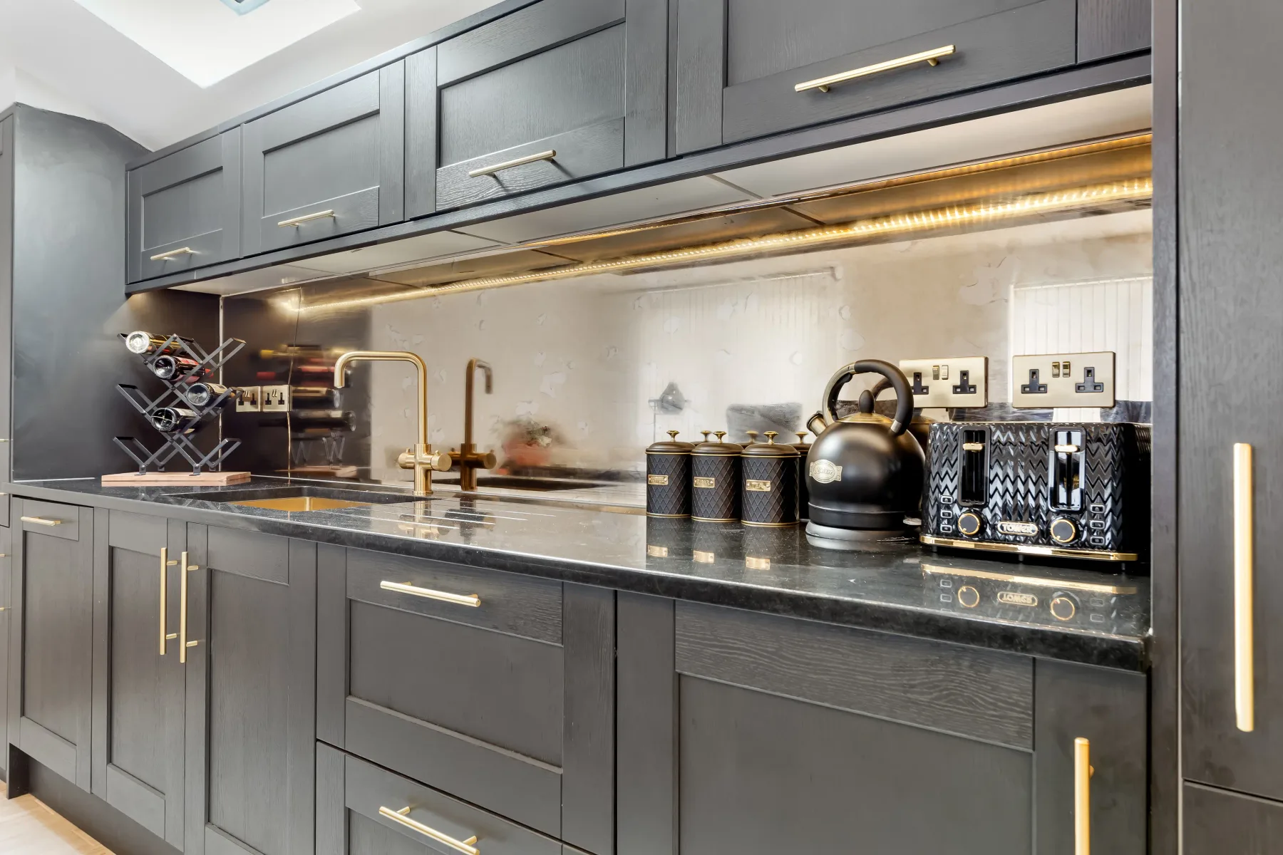 Una cocina moderna con gabinetes oscuros, una encimera y un hervidor.