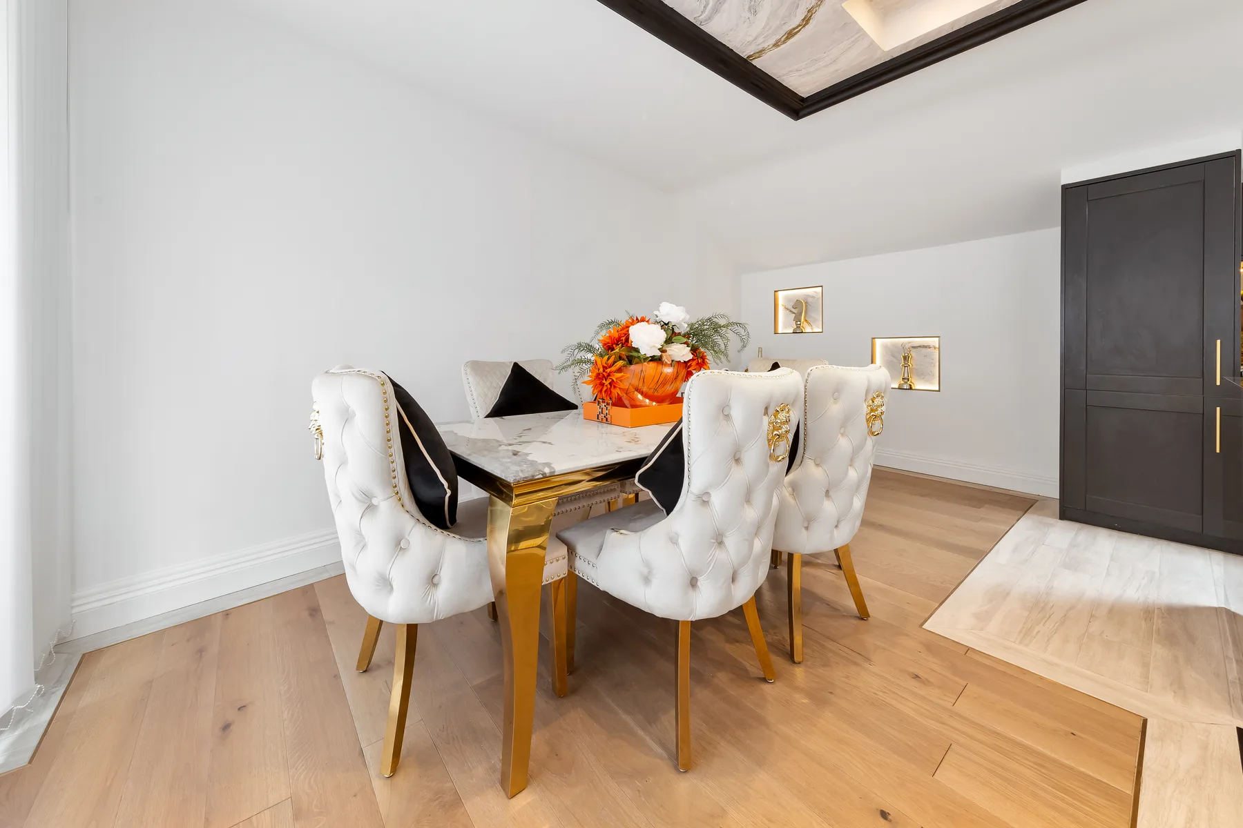 Comedor con una mesa oscura, asientos tapizados y un centro floral.
