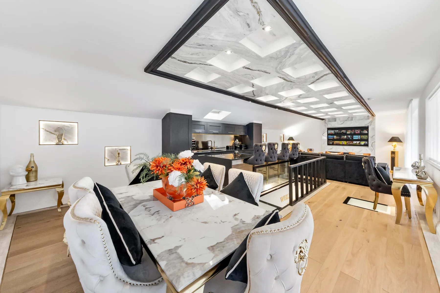 Un comedor y cocina diáfanos y luminosos, con una mesa de mármol y muebles oscuros.