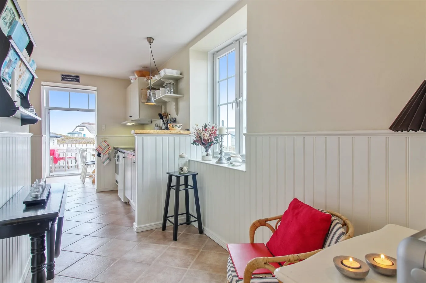 Una cocina y zona de comedor luminosa con una ventana que da a una terraza exterior.