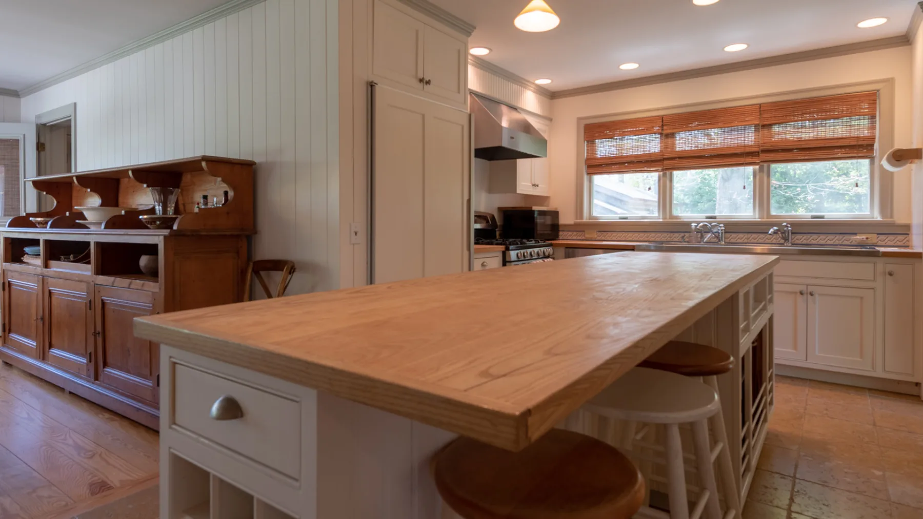 A spacious kitchen with a large wooden island and bar seating.