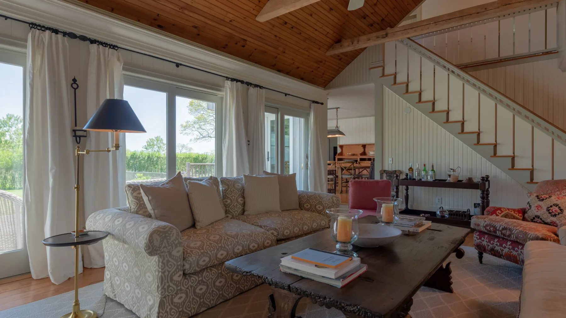 A living room with patterned seating, a coffee table, and a staircase.