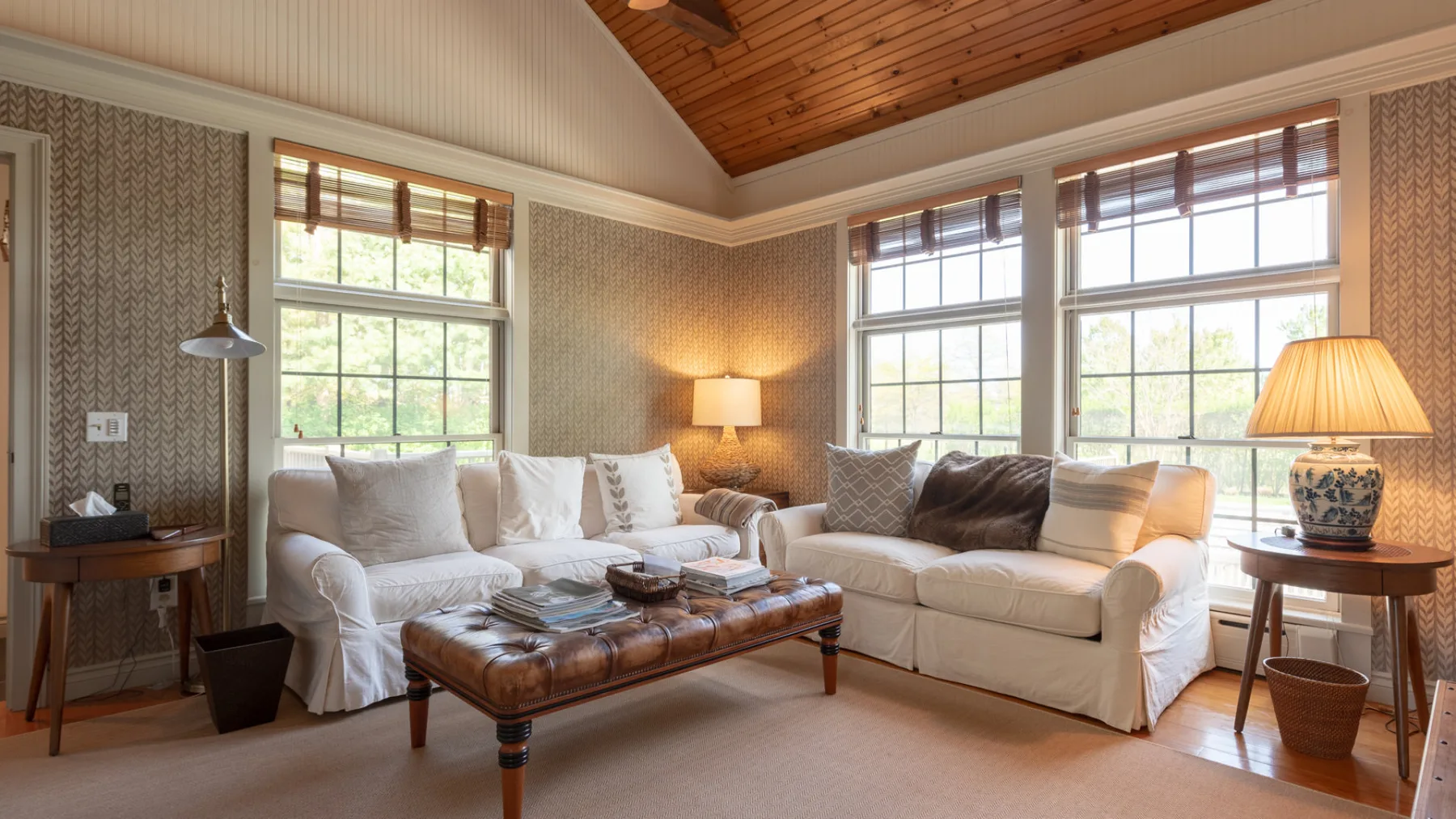 A living room with light-colored seating, a coffee table, and large windows.