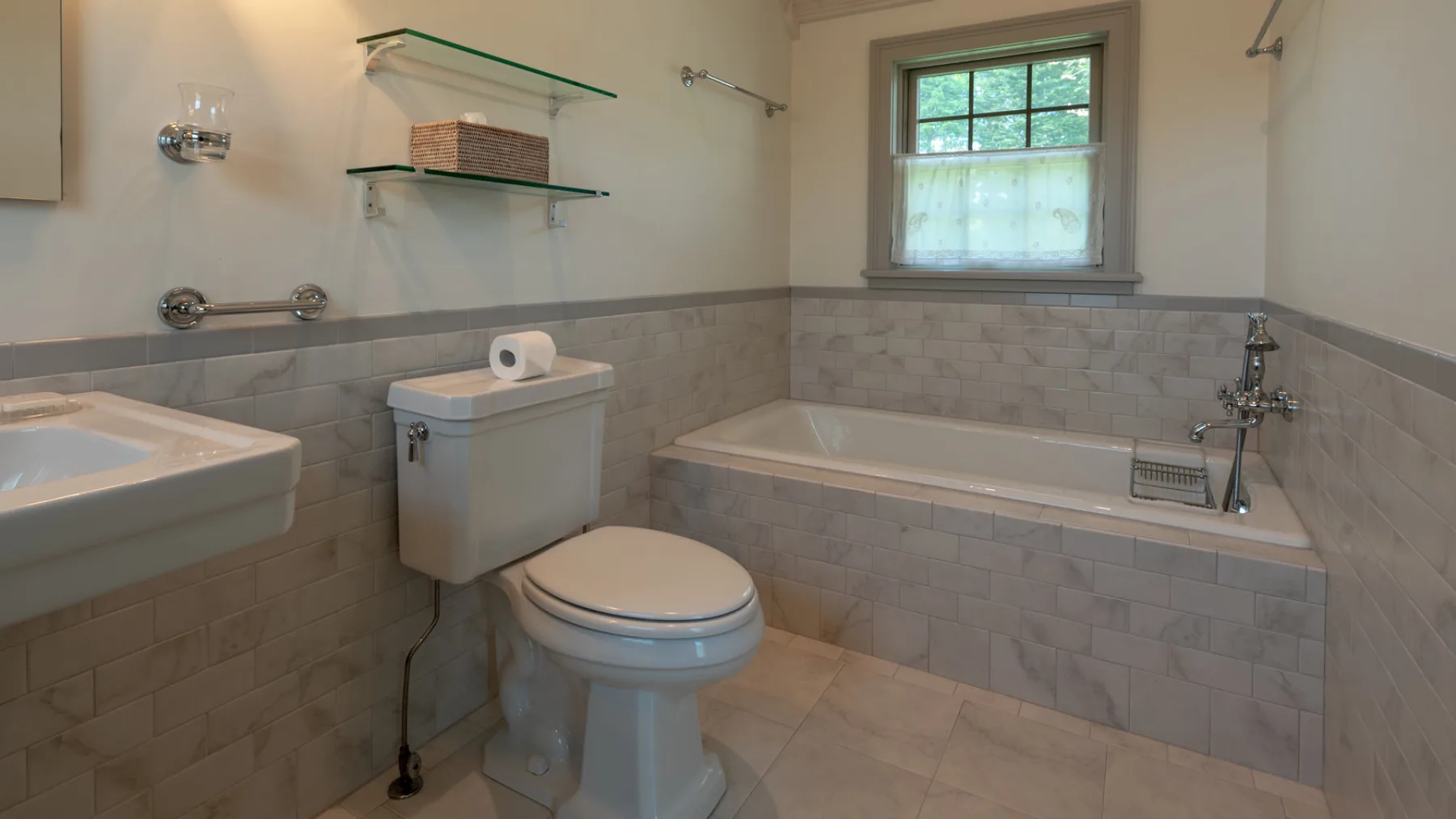 A bathroom with a bathtub, toilet, and frosted window.