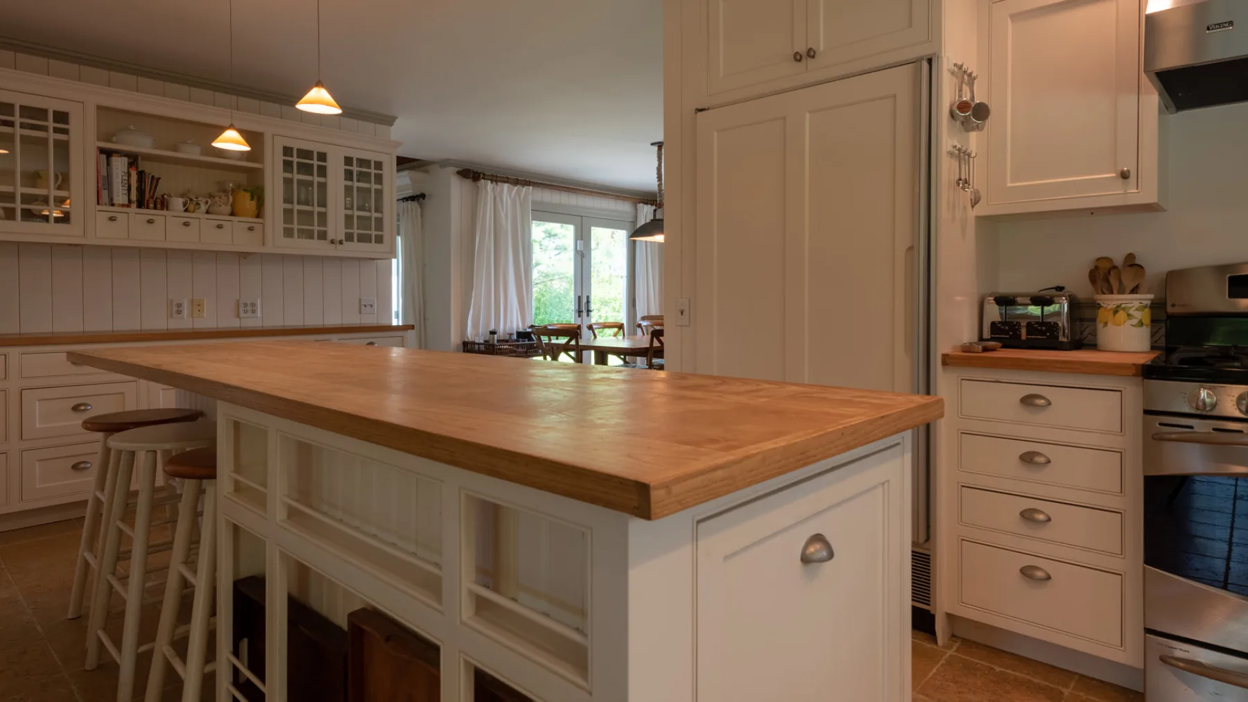 A bright kitchen with a large wooden island and white cabinetry.