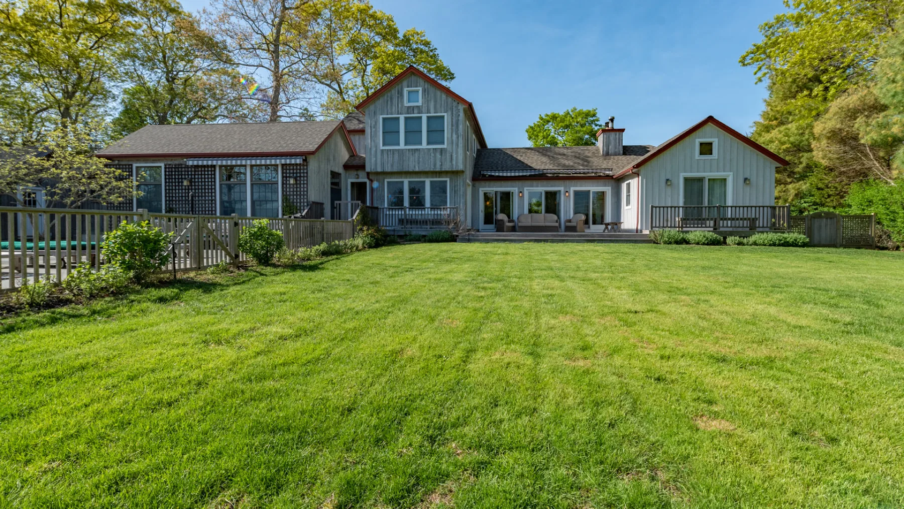 A large house overlooks a broad green lawn, with trees surrounding the property.